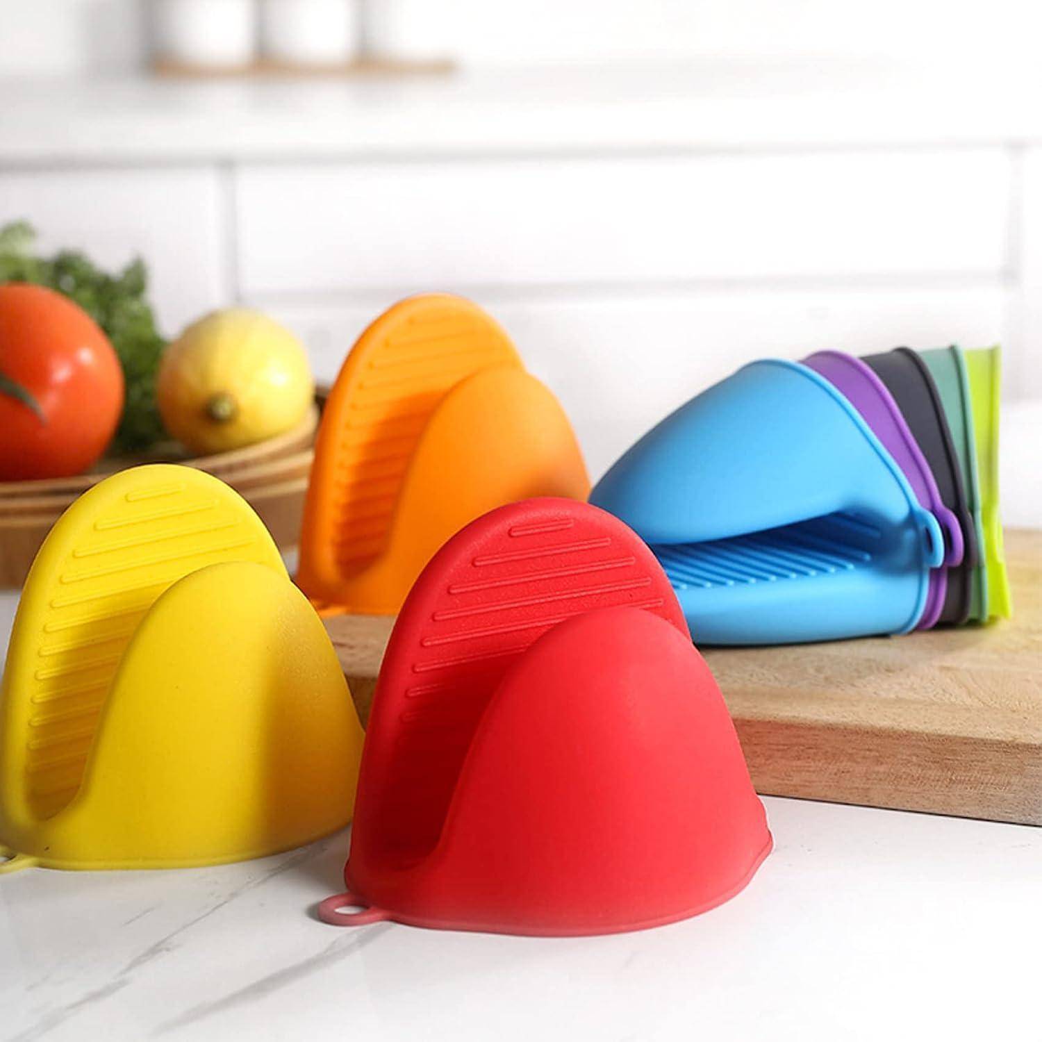 Bunte Silikoneierbecherhalter auf einer Küchentheke, mit gelben, orangefarbenen, roten, blauen, violetten und grünen Teilen, die in Stapeln angeordnet sind.