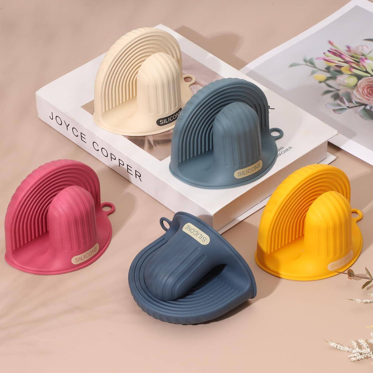 Fünf bunte silikon bogenförmige Schrubbürsten oder Spülschwämme auf einer Displaybox angeordnet, in rosa, creme, blaugrau, gelb und dunkelblau.