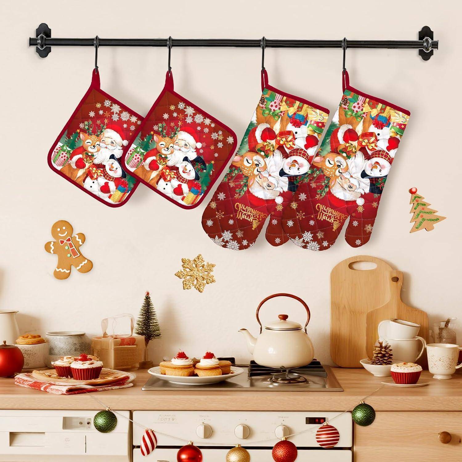 Weihnachtliche Küchendekoration mit vier Weihnachtsmannofenhandschuhen, die über einer festlichen Arbeitsplatte mit Cupcakes, Tassen und Weihnachtsdekoration hängen.