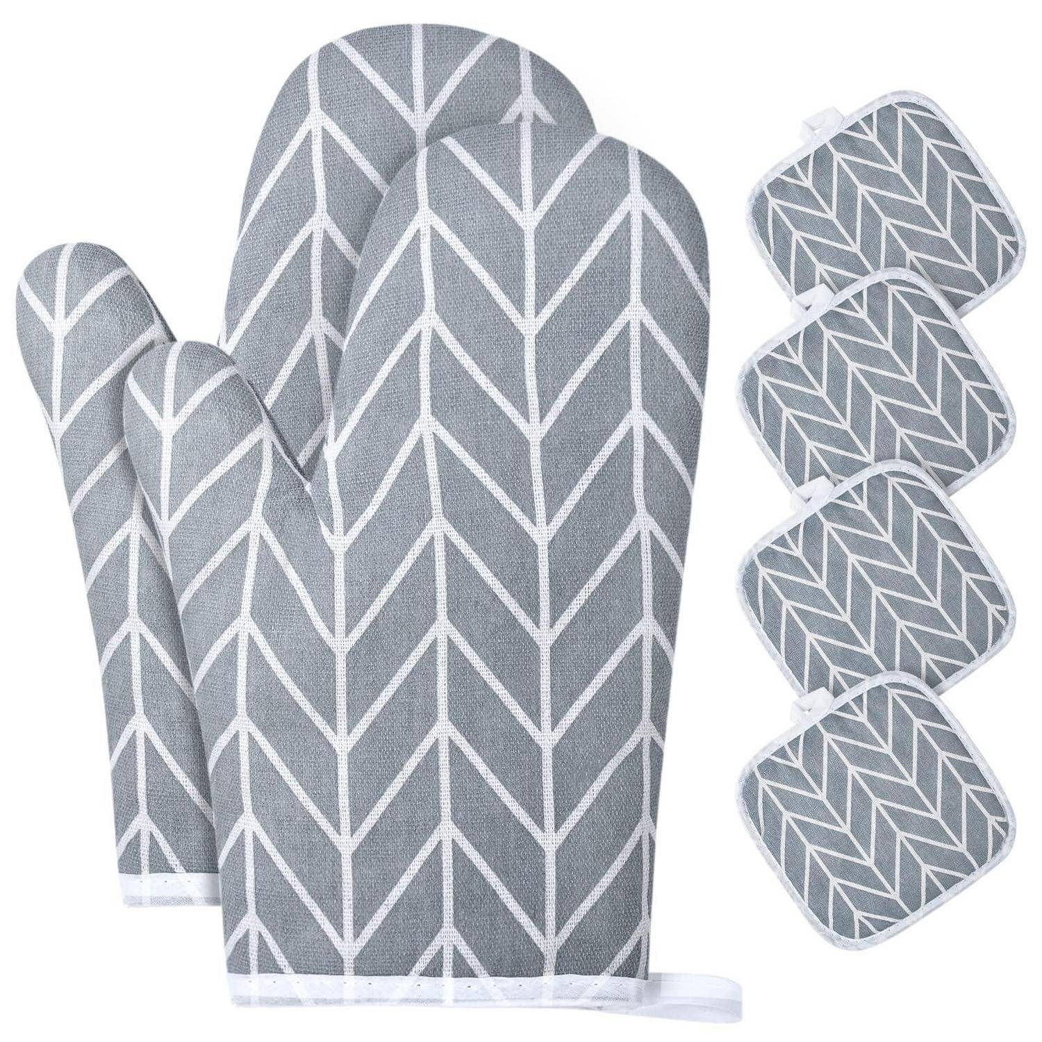 Grauer Topflappen mit Chevron-Muster und vier passende quadratische Untersetzer, angeordnet auf weißem Hintergrund.