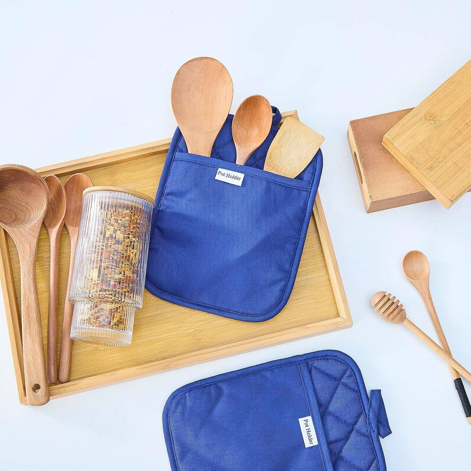 Blaue Utensilien-Taschen und hölzerne Küchengeräte auf Tabletts angeordnet, die ein Aufbewahrungsset für Löffel und Kochzubehör zeigen.