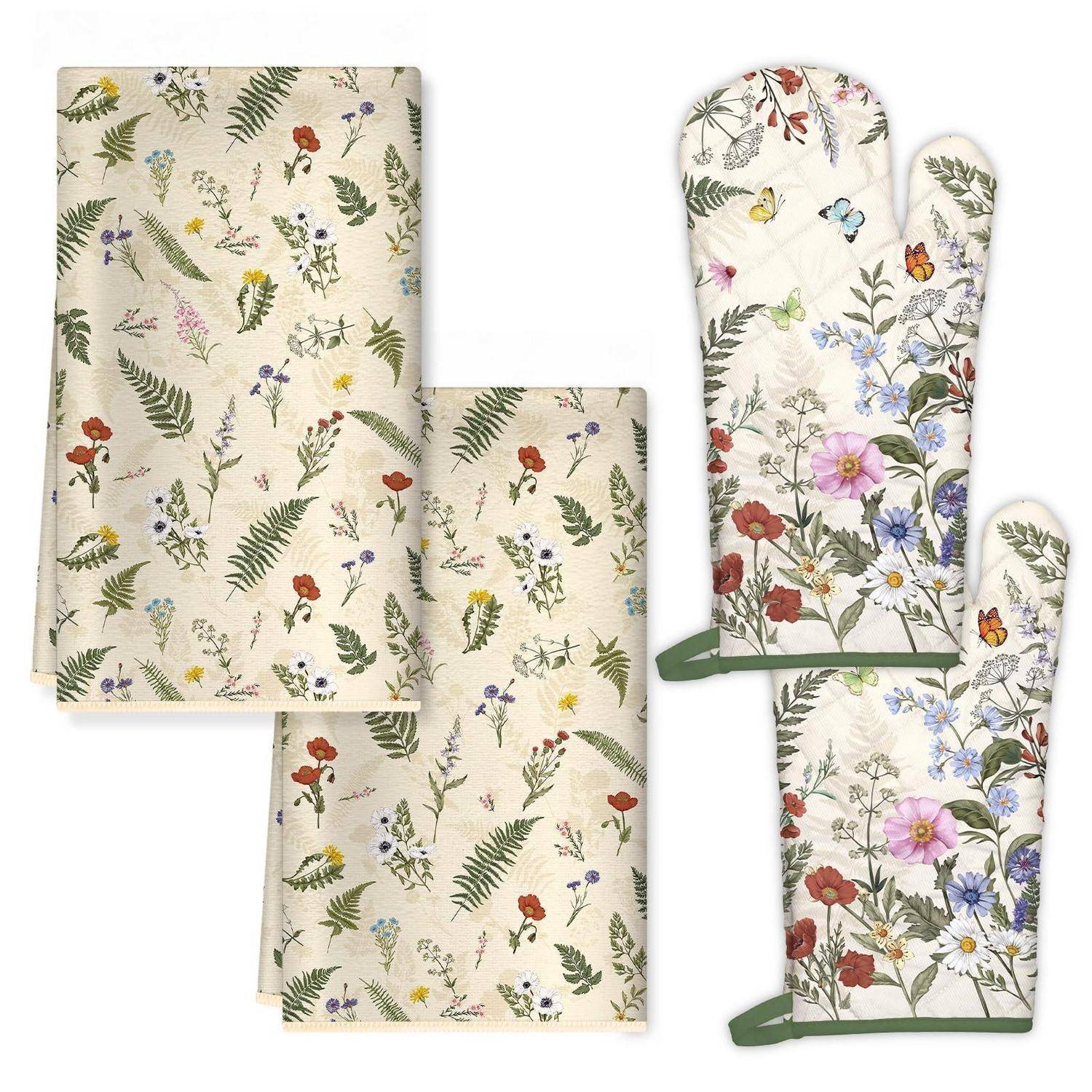 Stoffe mit Blumenmuster, einschließlich zwei gefalteter Textilien und zwei Ofenhandschuhen mit passendem botanischem Druck auf weißem Untergrund.