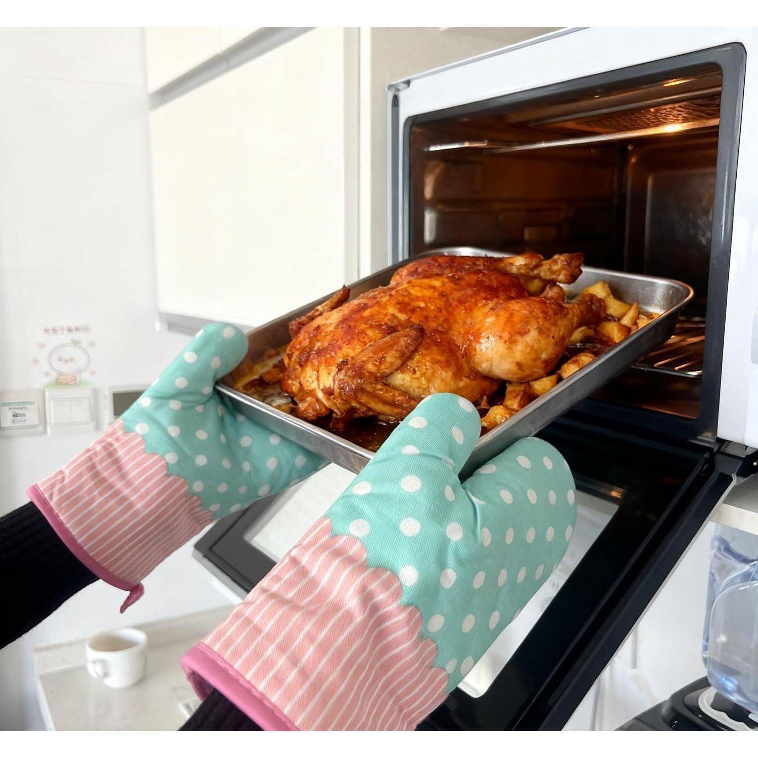 Hände in gepunkteten Ofenhandschuhen ziehen eine Bratpfanne mit einem gebratenen Huhn und Kartoffeln aus einem Ofen.