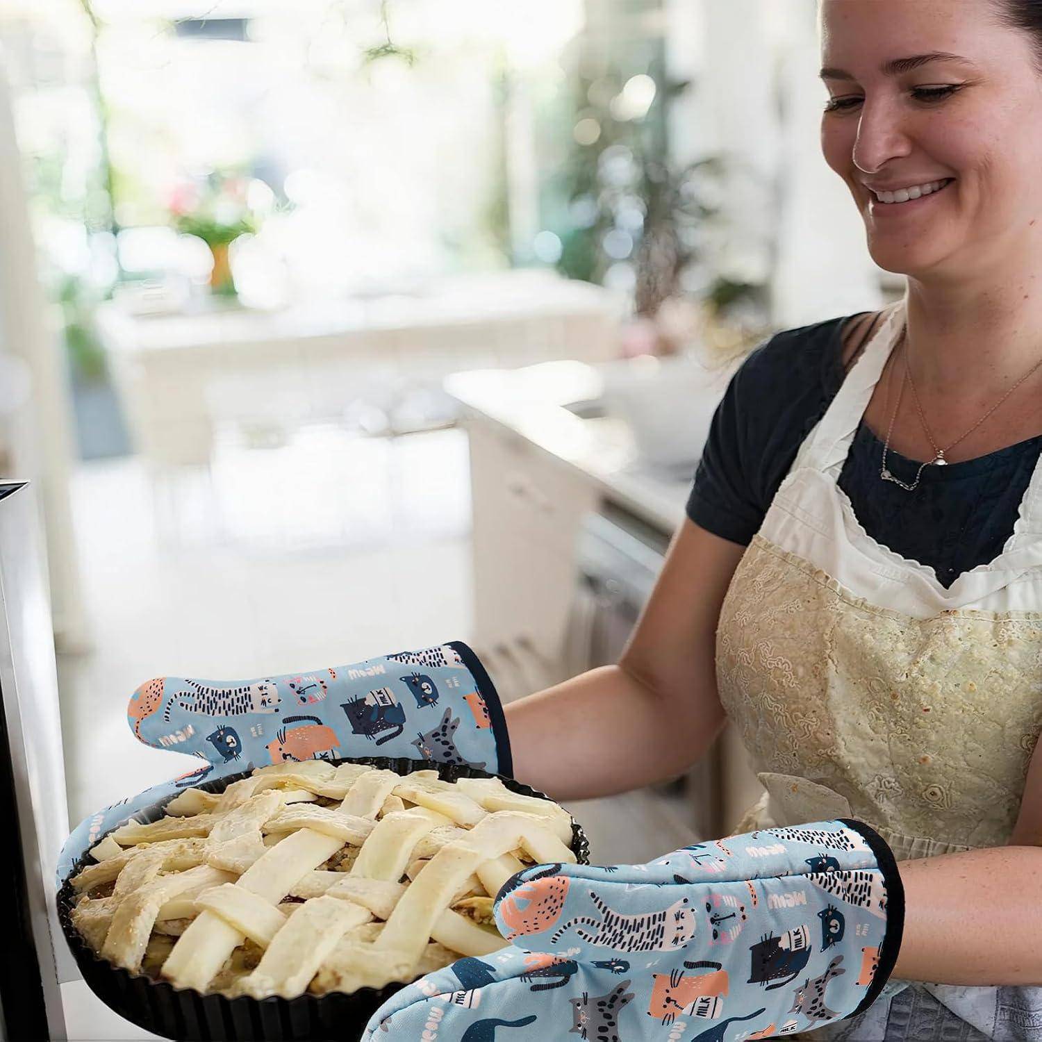 Lächelnde Frau in einer Schürze und Ofenhandschuhen hält einen Kuchen mit Gitterbelag in einer hellen Küche.