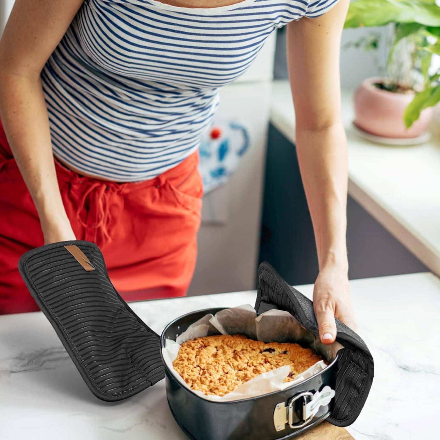 Eine Frau nimmt einen frisch gebackenen Streuselkuchen mit Ofenhandschuhen aus einer Springform in einer Küche heraus.