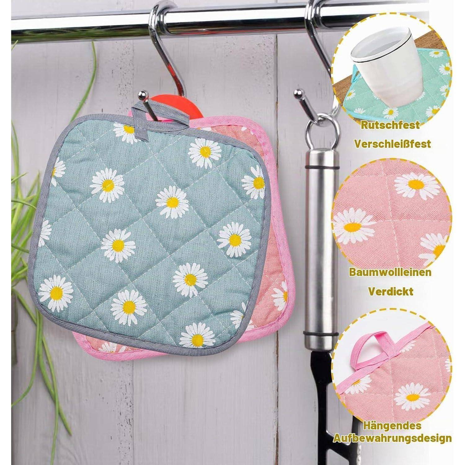 Zwei gesteppte Topfuntersetzer hängen an einem Metallhaken: blau mit Gänseblümchen vorne und rosa dahinter, mit drei Beschriftungen, die rutschfest, langlebige Baumwolle und hängende Aufbewahrung hervorheben.