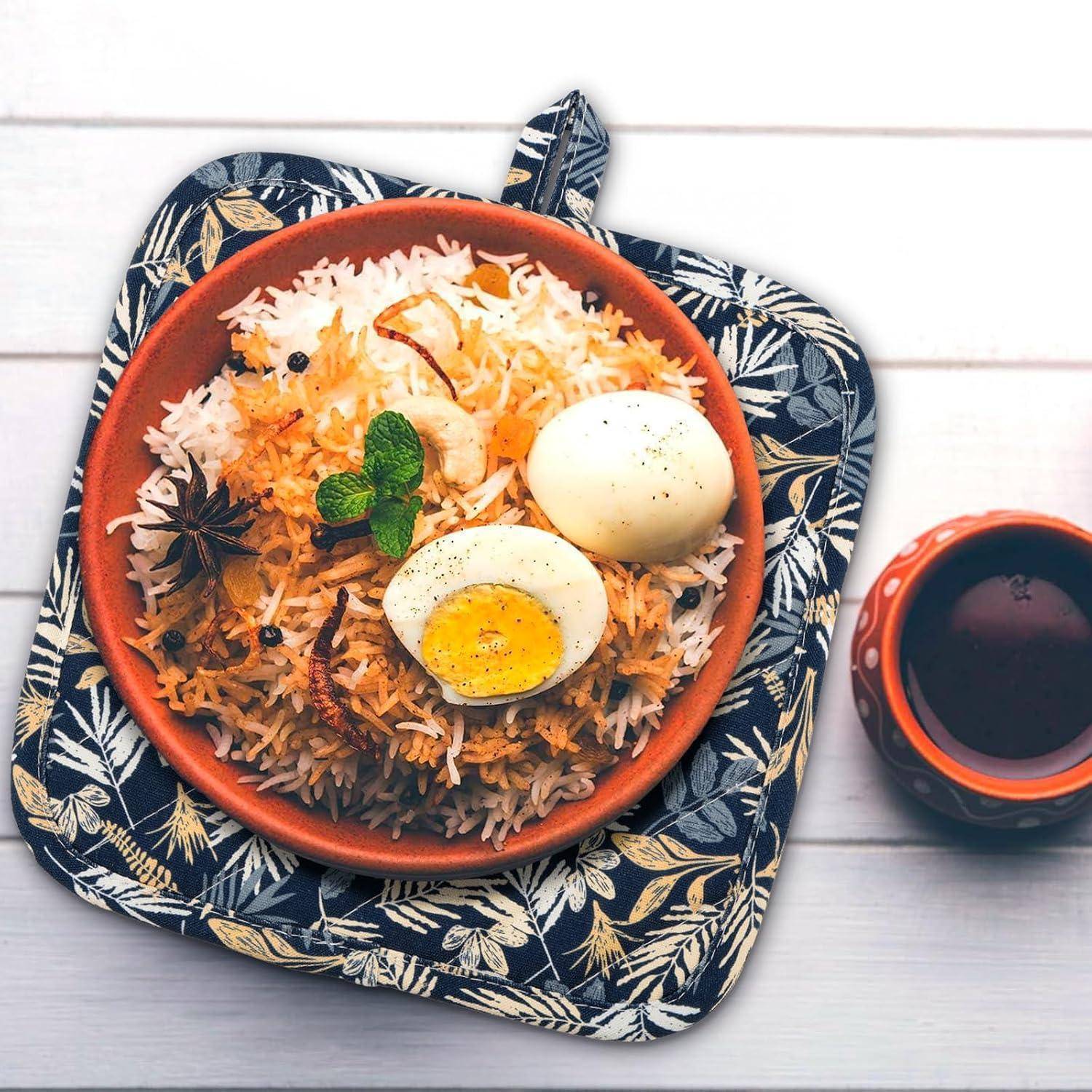 Schüssel Reis mit Eiern und Kräutern belegt auf einem gemusterten Tablett, mit einer Tasse dunkler Soße daneben.