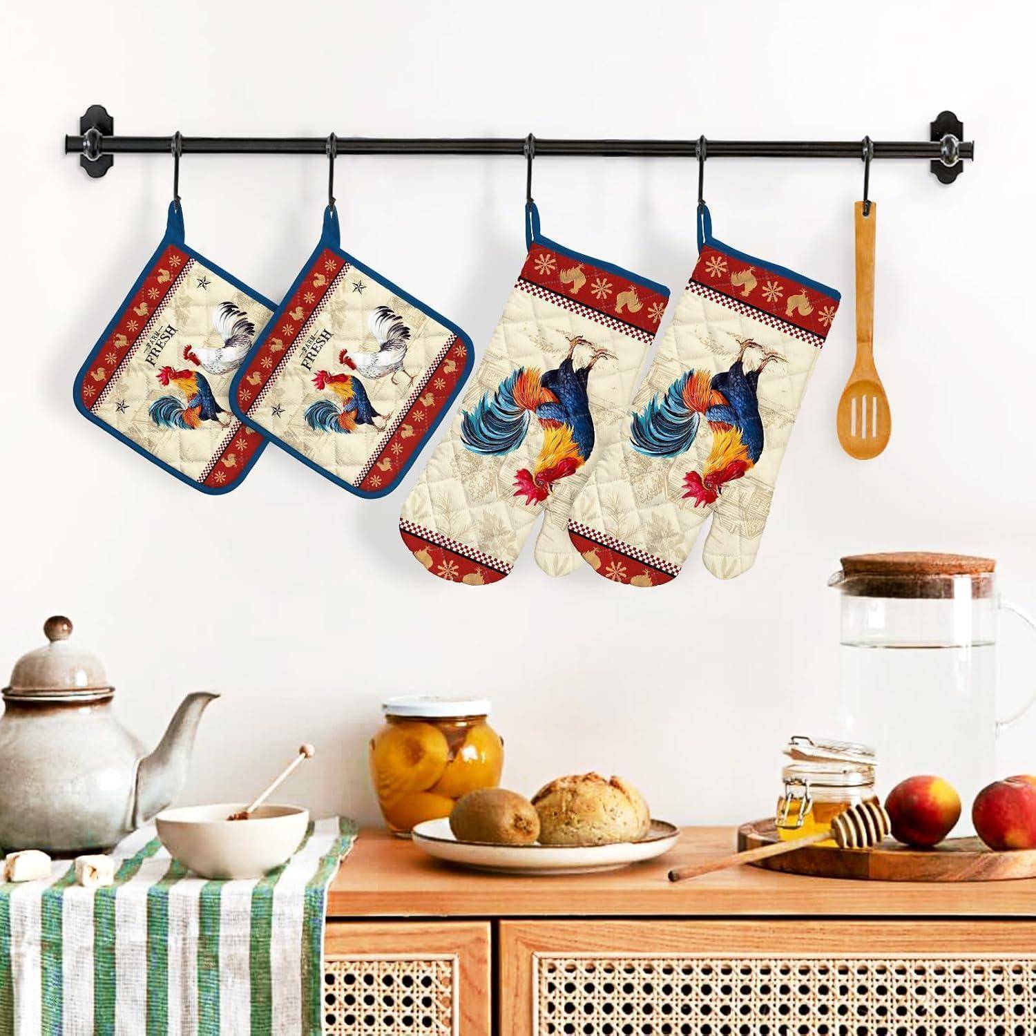 Küchenwand mit hängenden Ofenhandschuhen mit Hahnmuster und einem Holzlöffel über einem Tisch mit Teekanne, Schüssel, Brot, Obst und Gläsern.