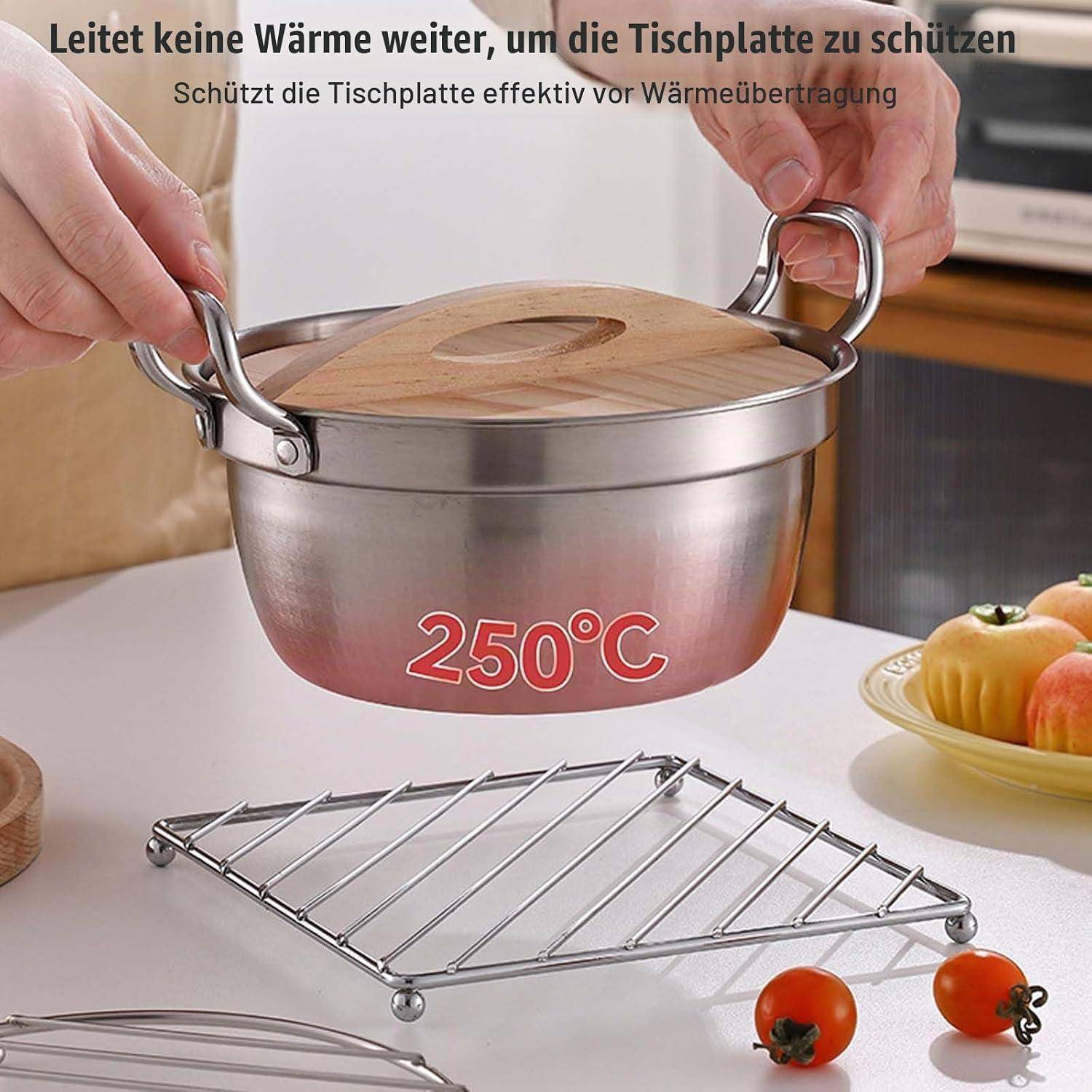 Hände heben einen Topf mit Holzdeckel über einen Metallständer, wobei 