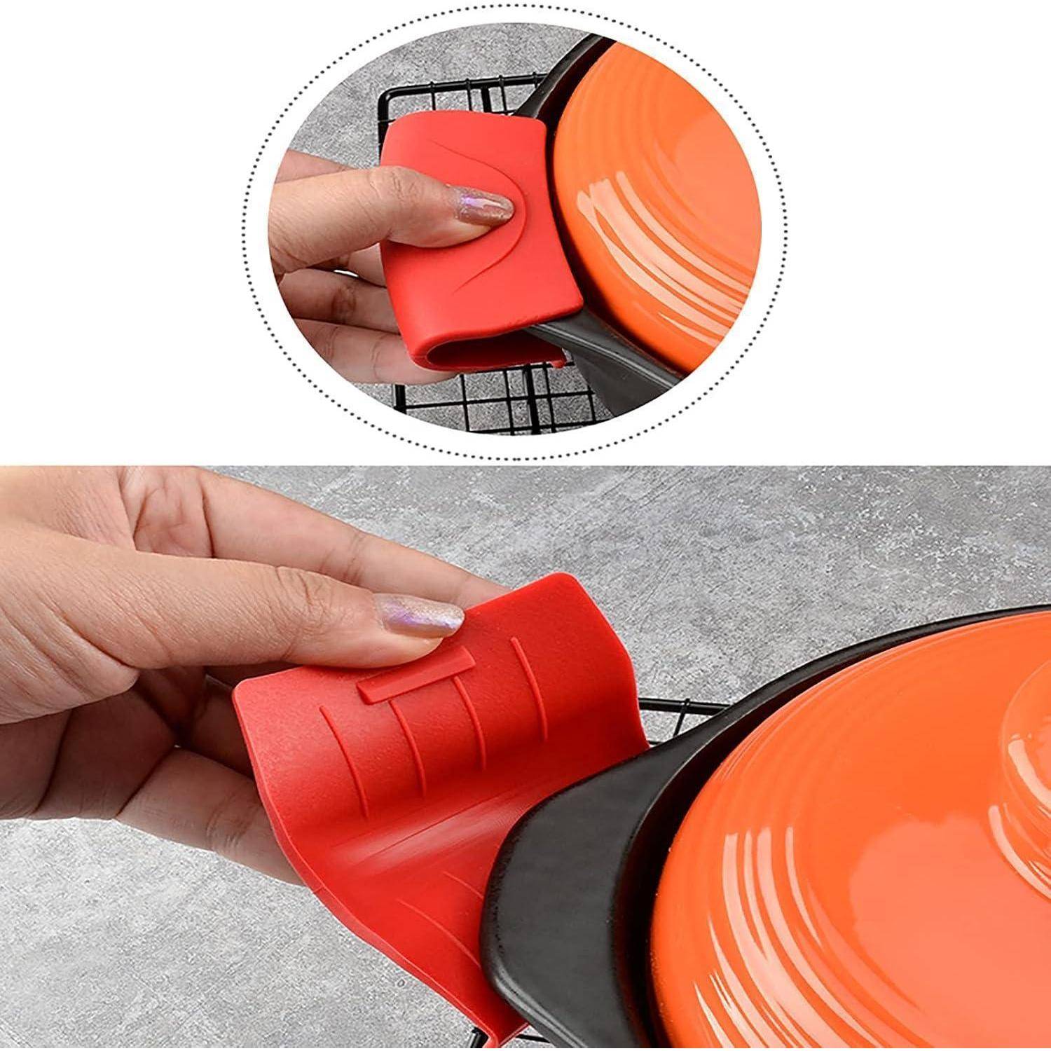 Eine Hand legt eine rote Silikongriffschutzhülle auf den heißen Griff einer Pfanne, um sich beim Kochen vor der Hitze zu schützen.