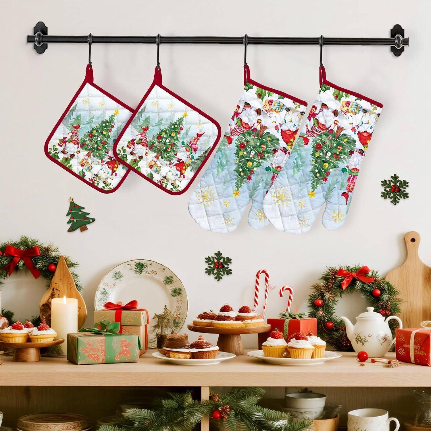 Festliche Weihnachtsküchenausstellung mit vier Urlaubs-Ofenhandschuhen, die über einem Tisch mit Desserts, Geschenken, Kranz, Kerze und Teekanne hängen.