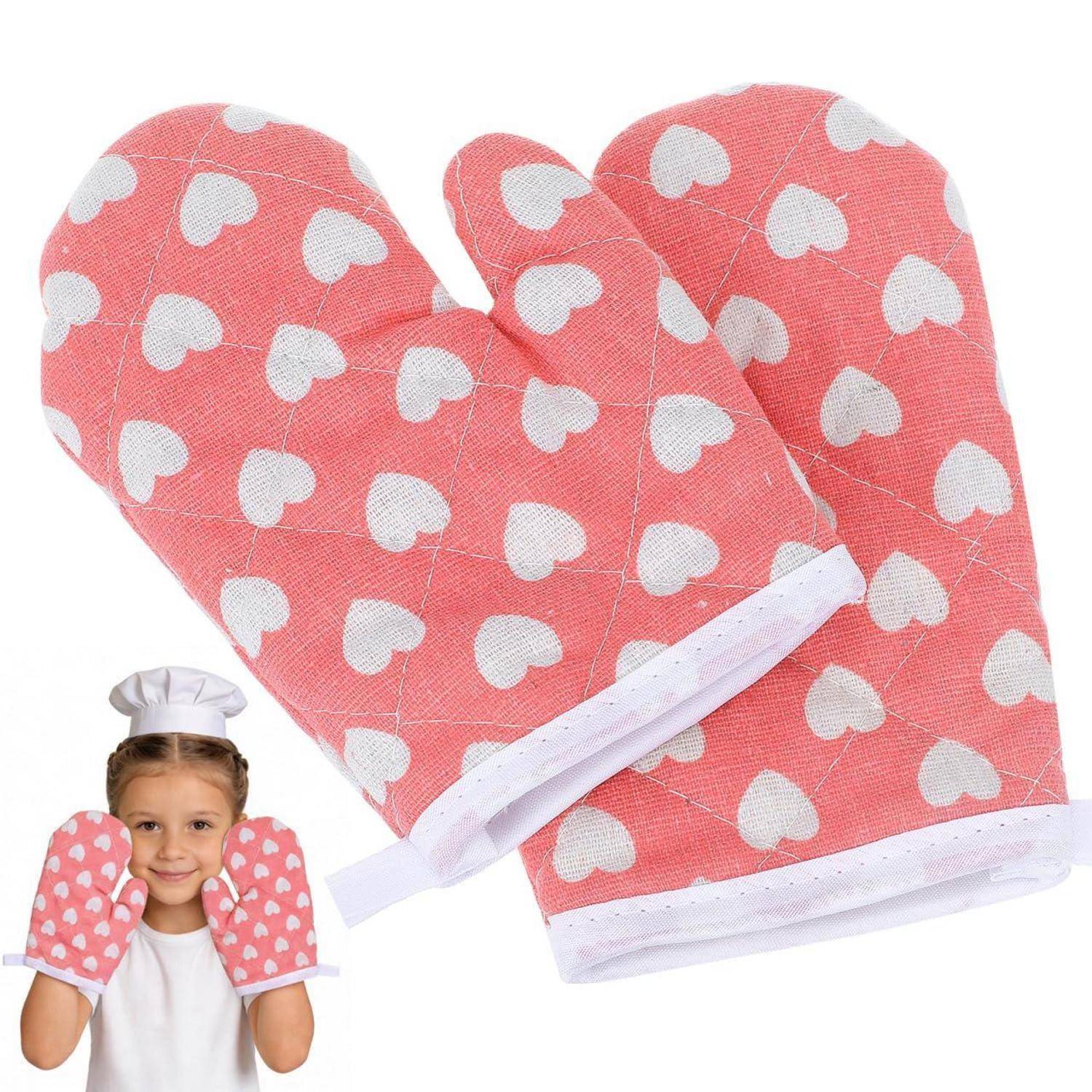 Rosa Ofenhandschuhe mit weißem Herzmuster, groß abgebildet neben einem lächelnden Kind, das die gleichen Handschuhe trägt.