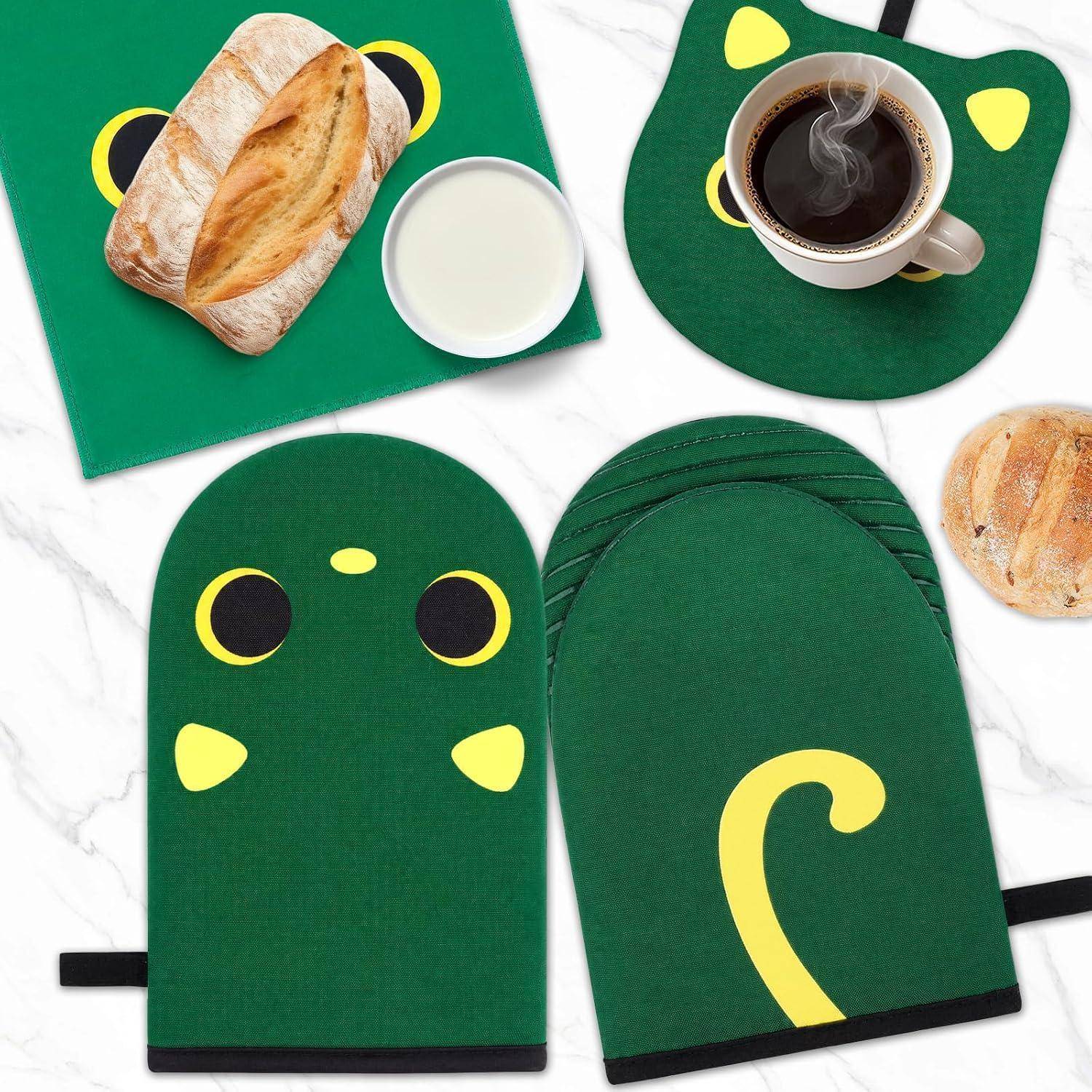 Grüne, katzenförmige Platzdeckchen mit gelben Ohren und Augen umgeben Brot, Milch und eine dampfende Kaffeetasse auf einer weißen Oberfläche.