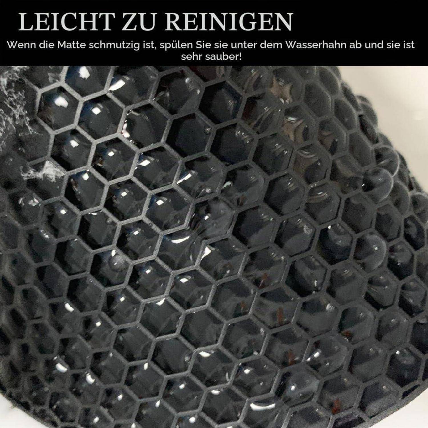 Nahaufnahme einer schwarzen sechseckigen Matte mit Wassertropfen; deutscher Text besagt, dass sie leicht zu reinigen ist, indem man sie unter Wasser abspült.