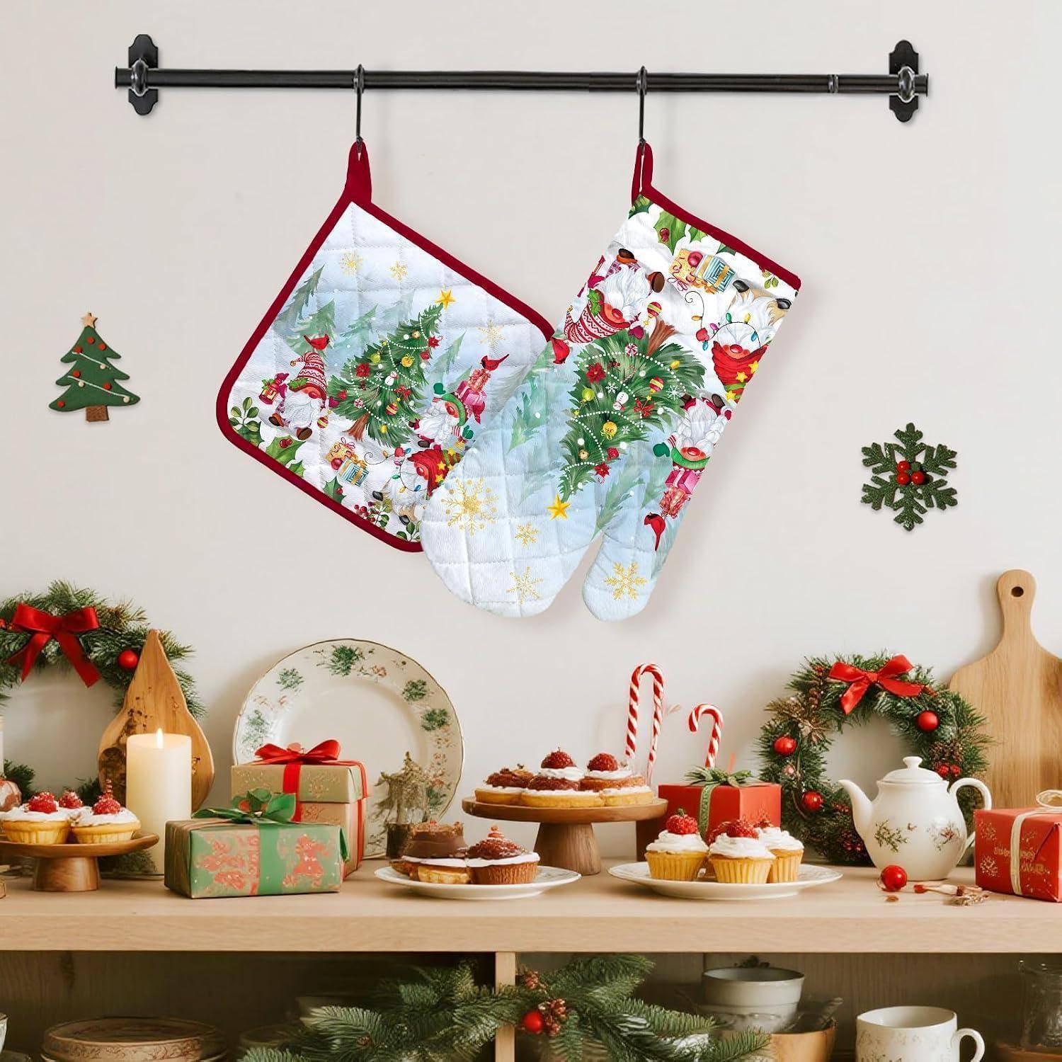 Weihnachtliche Küchendekoration mit zwei hängenden Feiertagsofenhandschuhen über einem Tisch mit festlichen Desserts, Geschenken, Kränzen, Kerzen und Tischbesteck.