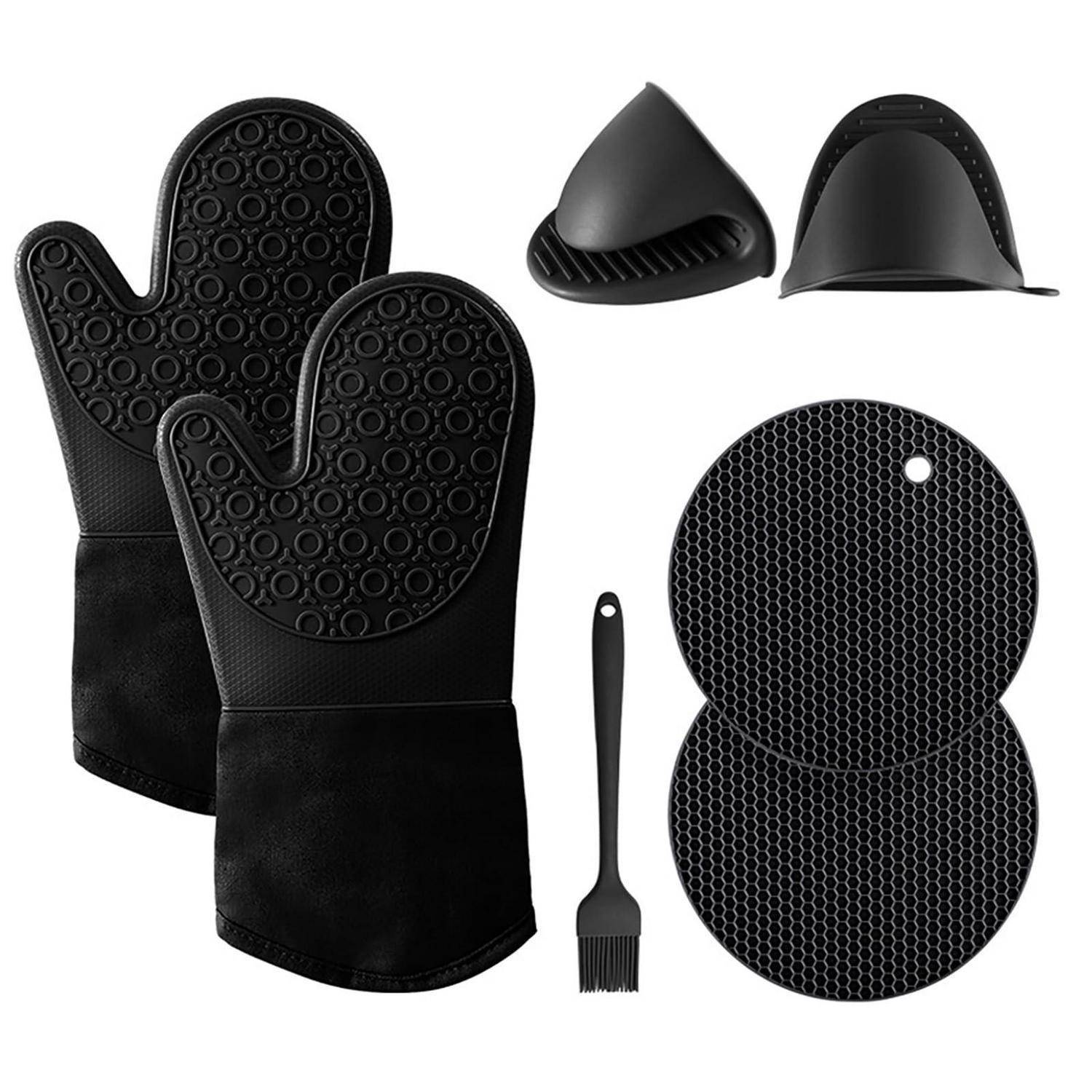 Schwarze Silikon-Ofenhandschuhe, ein Spatel und zwei runde Silikonmatten auf weißem Hintergrund angeordnet.