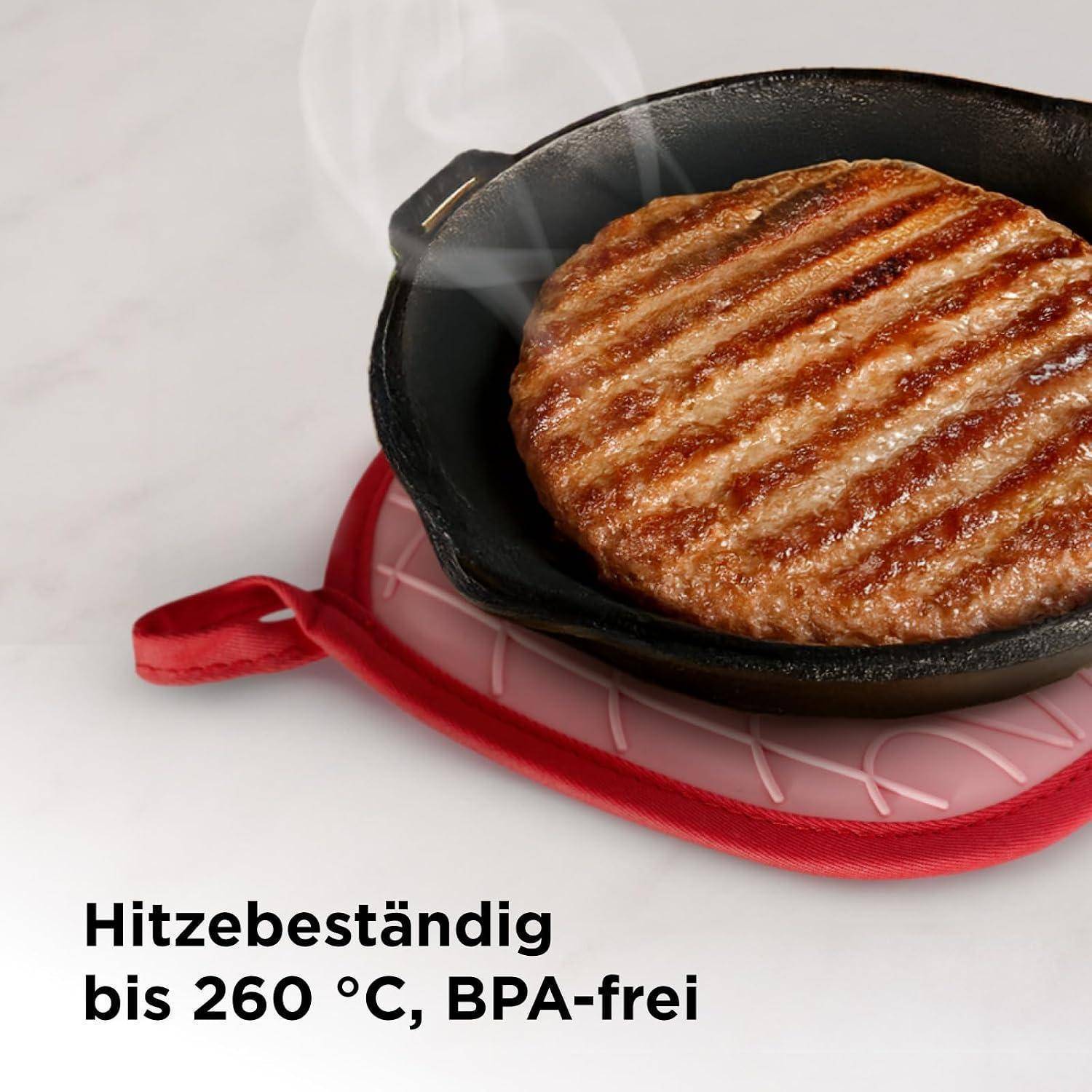 Gegrilltes Burgerpattie in einer gusseisernen Pfanne auf einer roten hitzebeständigen Matte, mit deutschem Text, der lautet: „Hitzebeständig bis 260 °C, BPA-frei
