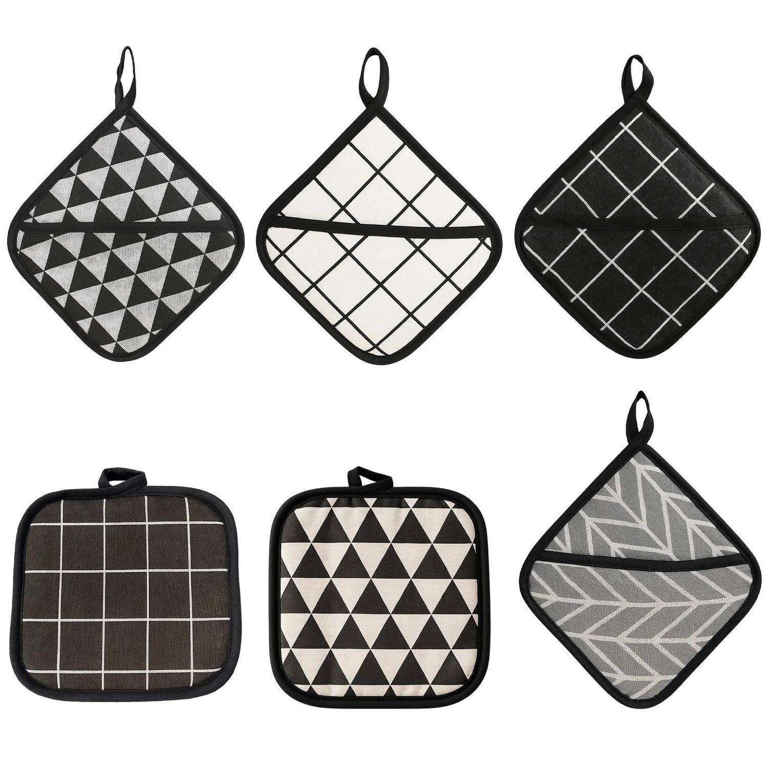 Sechs gesteppte Topflappen mit verschiedenen schwarzen, weißen und grauen geometrischen Mustern auf weißem Hintergrund.
