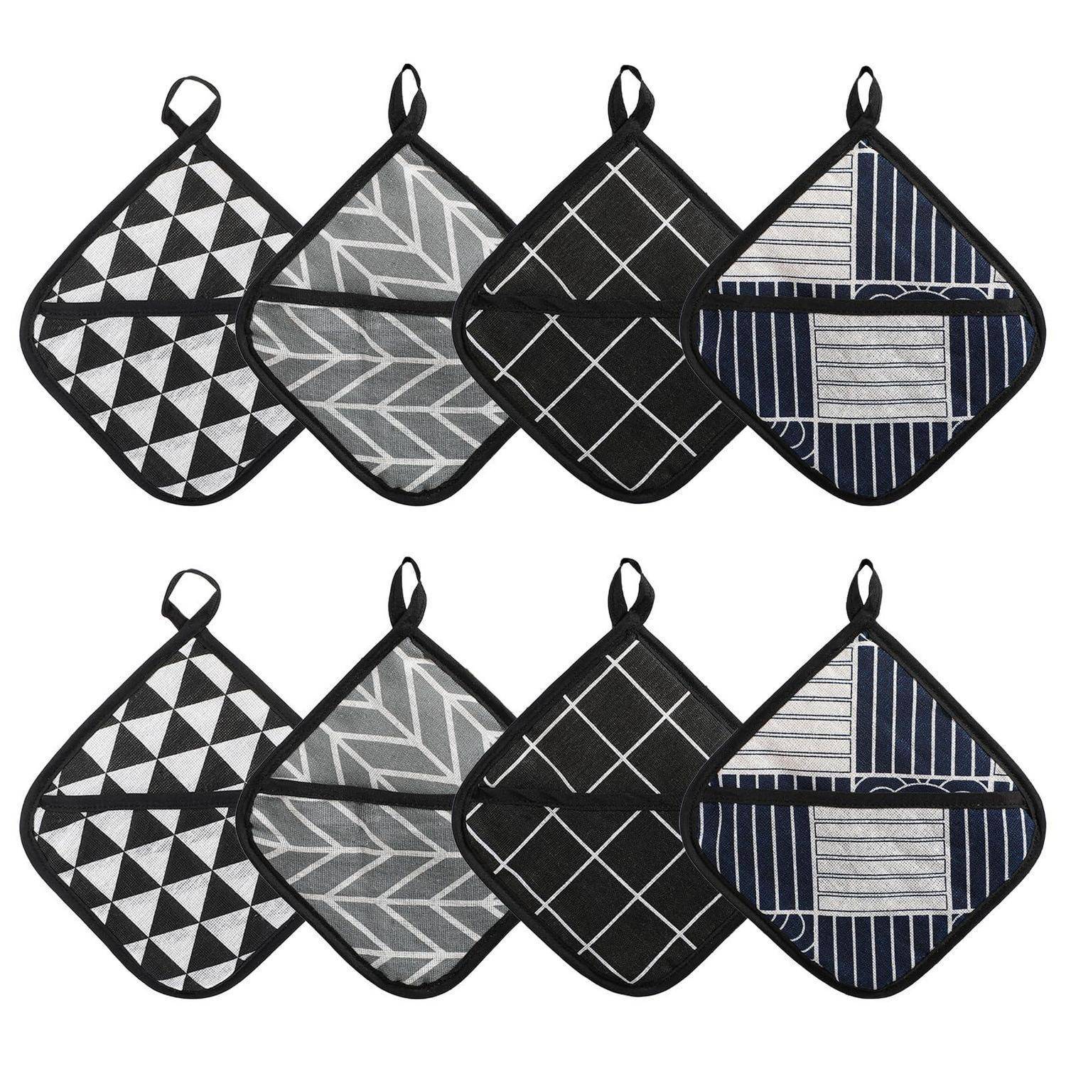 Acht gesteppte quadratische Topflappen in zwei Reihen, die schwarze, graue und dunkelblaue geometrische Muster mit Aufhängeschleifen zeigen.