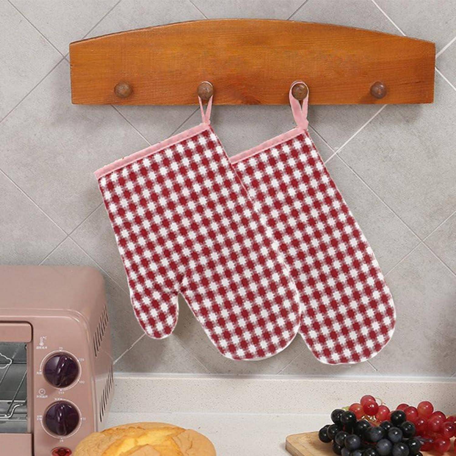 Zwei rot-weiß karierte Topflappen hängen an einem Holzregal über einer Küchenarbeitsplatte.