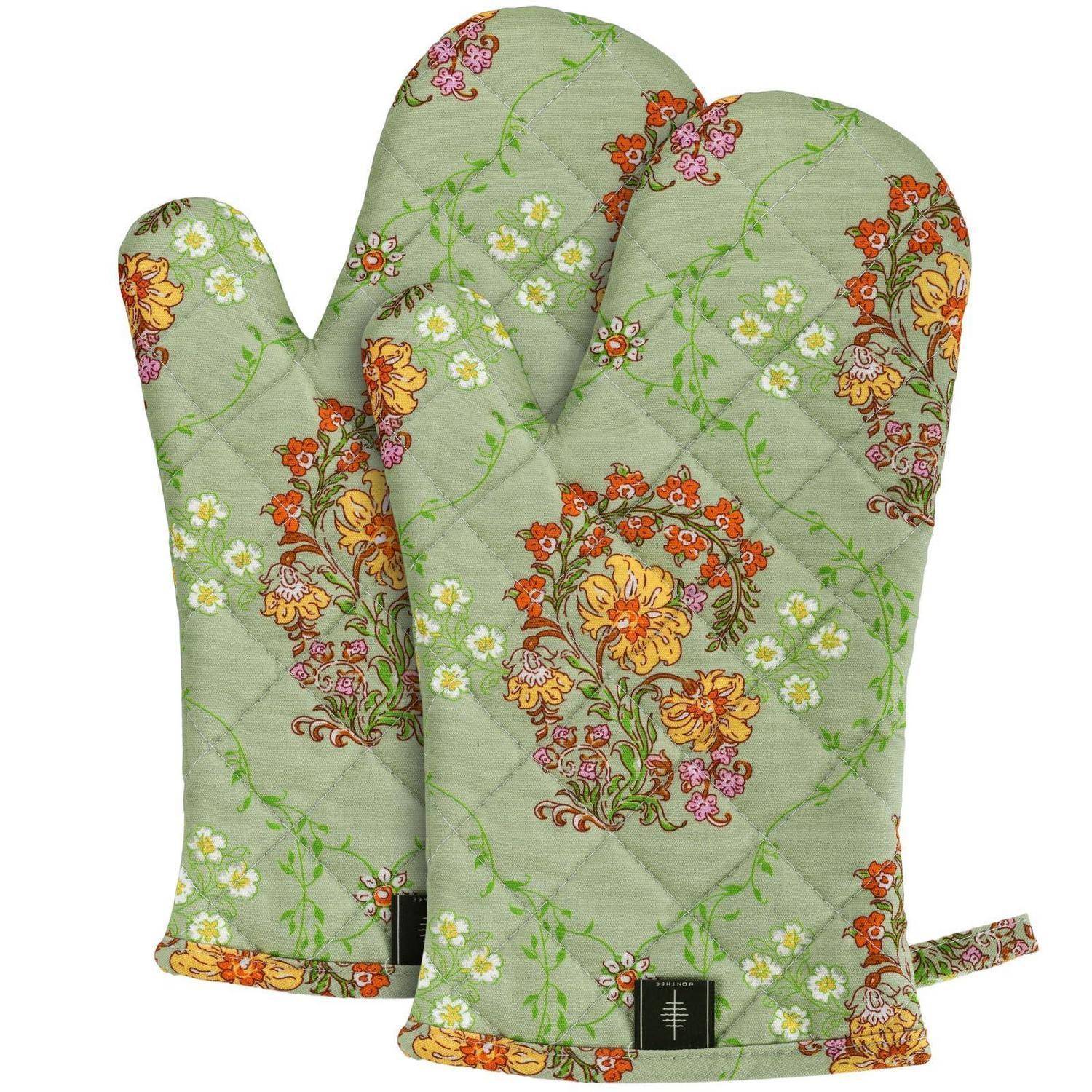 Paar grüne gesteppte Ofenhandschuhe mit Blumenmuster und Aufhängeschlaufe, gezeigt auf weißem Hintergrund.