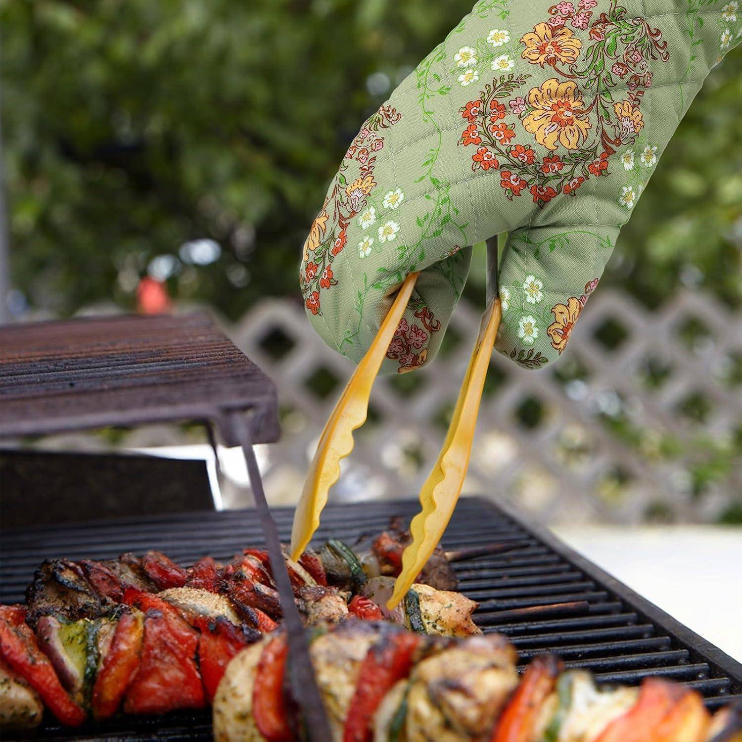 Eine behandschuhte Hand benutzt gelbe Zangen, um gegrilltes Gemüse auf einem Grillrost im Freien zu wenden.