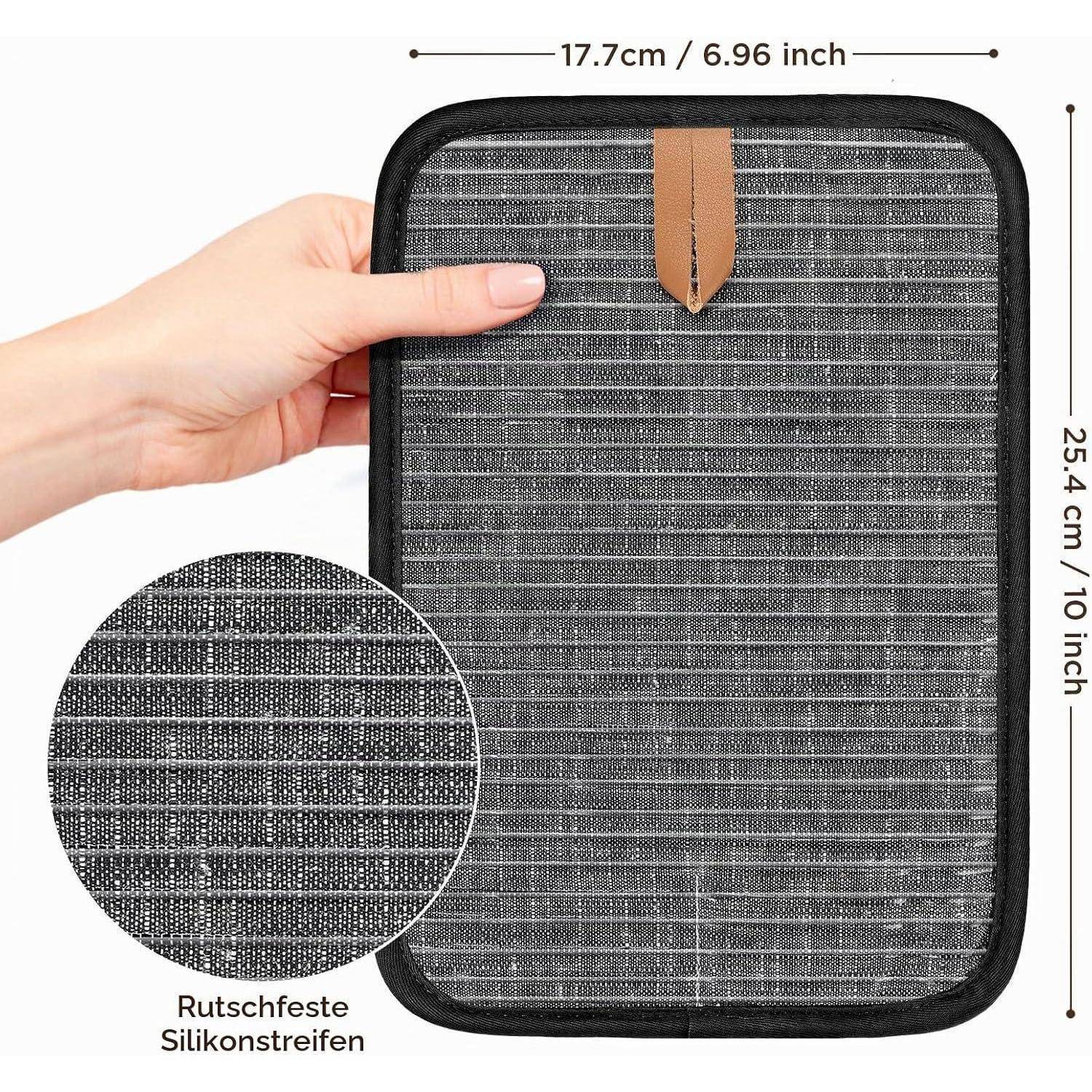 Rechteckiger gepolsterter Koffer mit schwarzem Rand und brauner Aufhängungsschlaufe, mit einer Hand zur Größendarstellung gezeigt; mit den Maßen 17,7 cm x 25,4 cm beschriftet und Detailausschnitt „Rutschfeste Silikonstreifen