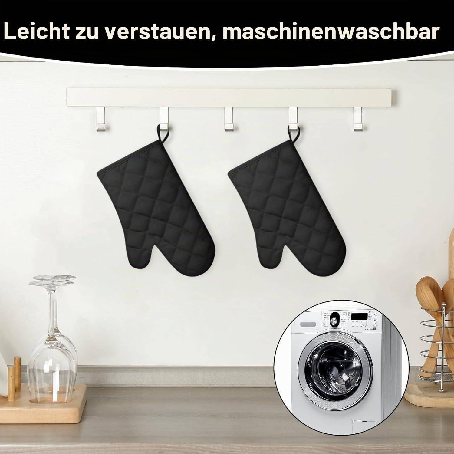 Zwei schwarze gesteppte Ofenhandschuhe hängen an einem Wandgestell in einer Küche; die Vergrößerung zeigt eine Frontlader-Waschmaschine. Der Text lautet „Leicht zu verstauen, maschinenwaschbar