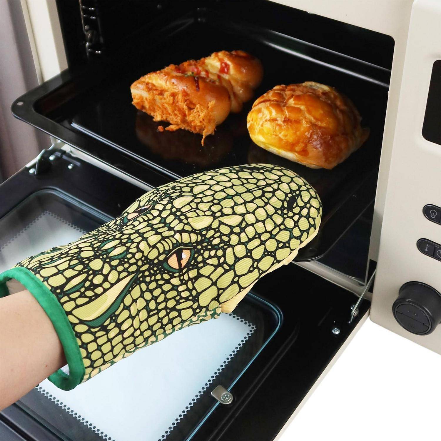 Eine Hand mit einem Ofenhandschuh nimmt ein Backblech mit zwei Brötchen aus einem Toasterofen.
