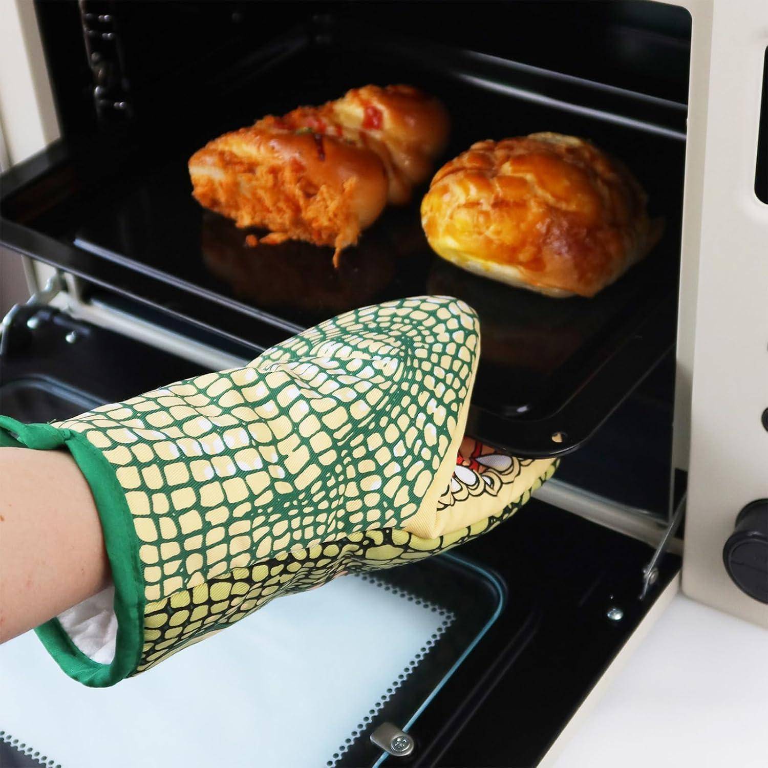 Handschuhe tragende Hand nimmt ein Backblech mit zwei Gebäckstücken aus dem Ofen.