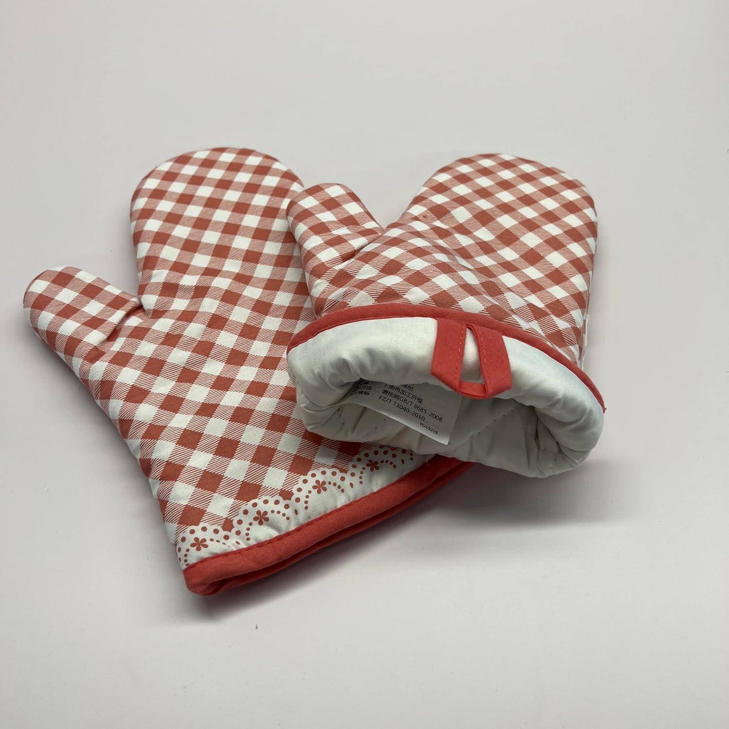 Paar rot-weiß karierter Ofenhandschuhe mit gesteppter Polsterung und Aufhängeschleifen auf einfachem Hintergrund.