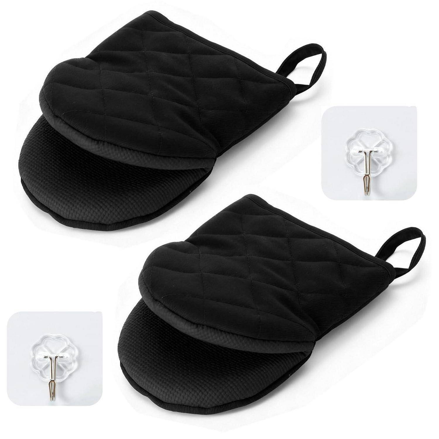 Zwei schwarze gesteppte Ofenhandschuhe mit Aufhängeschleifen und wärmefesten strukturierten Handflächen, gezeigt mit im Lieferumfang enthaltenen selbstklebenden Wandhaken.