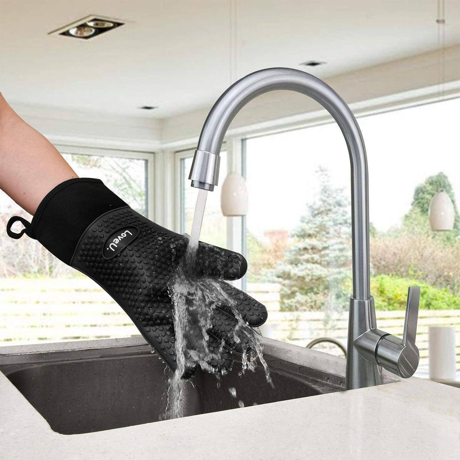 Eine Person, die einen schwarzen Ofenhandschuh trägt, spült ihn unter einem Küchenwasserhahn in einem Spülbecken ab.