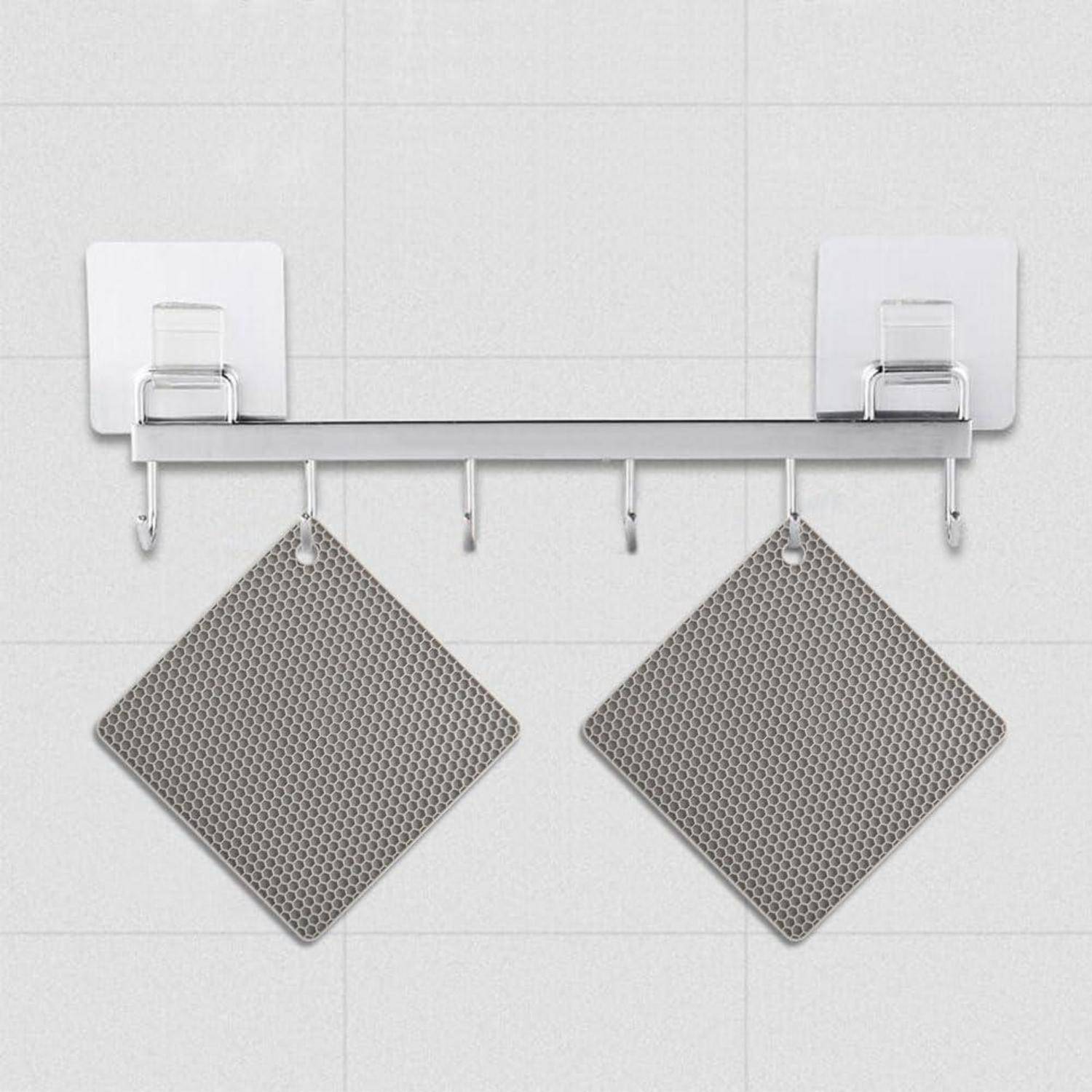 Wandmontiertes Handtuchregal mit zwei aufgehängten grauen strukturierten Badematten oder Handtüchern an weiß gekachelter Wand.