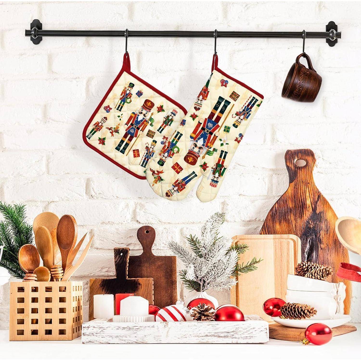 Weihnachtliche Küchendisplay mit Nussknacker-Muster-Ofenhandschuhen, die über hölzernen Küchenutensilien, Schneidebrettern, Tassen, Tannenzapfen und roten Weihnachtskugeln hängen.