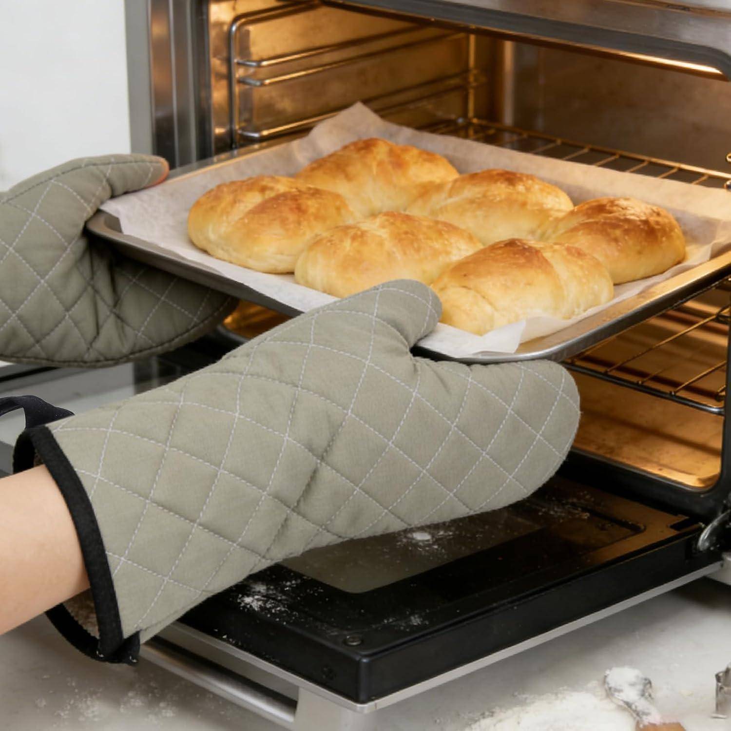 Person mit Ofenhandschuhen zieht ein Tablett mit frisch gebackenen Brötchen aus dem Ofen.