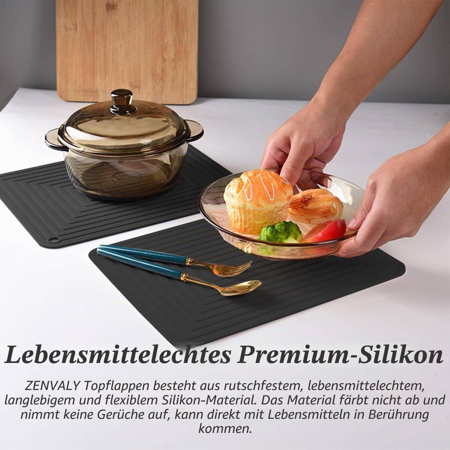 Hände stellen einen Teller mit Essen auf eine schwarze Silikon-Untersetzer neben einen Glastopf und Besteck; Deutscher Text wirbt für lebensmittelsicheres Premium-Silikon.