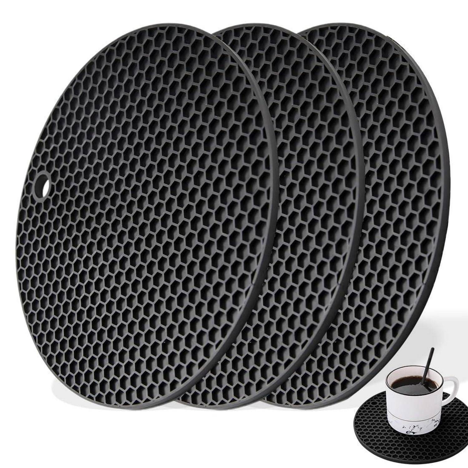 Drei schwarze Wabenmuster-Untersetzer in runder Form mit einer kleinen Tasse Kaffee, die hitzebeständige Getränkeunterlagen zeigen.