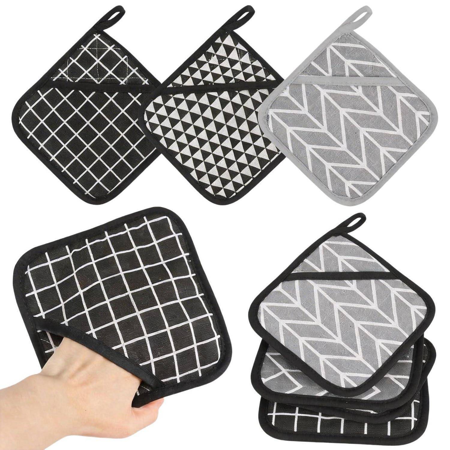 Satz von gemusterten gesteppten Topflappen, einschließlich eines, das von einer Hand gehalten wird, mit schwarzen und grauen geometrischen Designs.