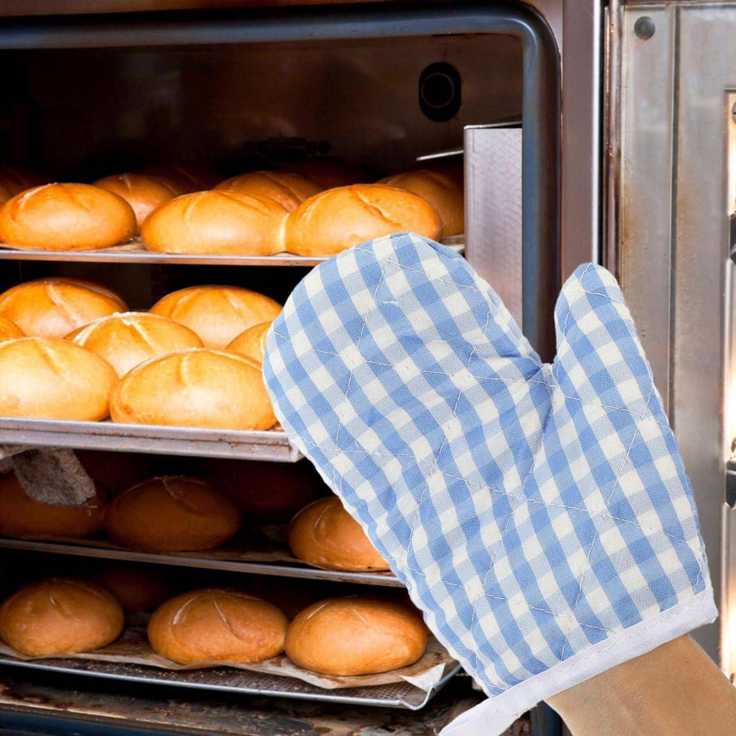Ofenroste mit frisch gebackenen Brötchen werden mit einem blaukarrierten Ofenhandschuh herausgezogen.