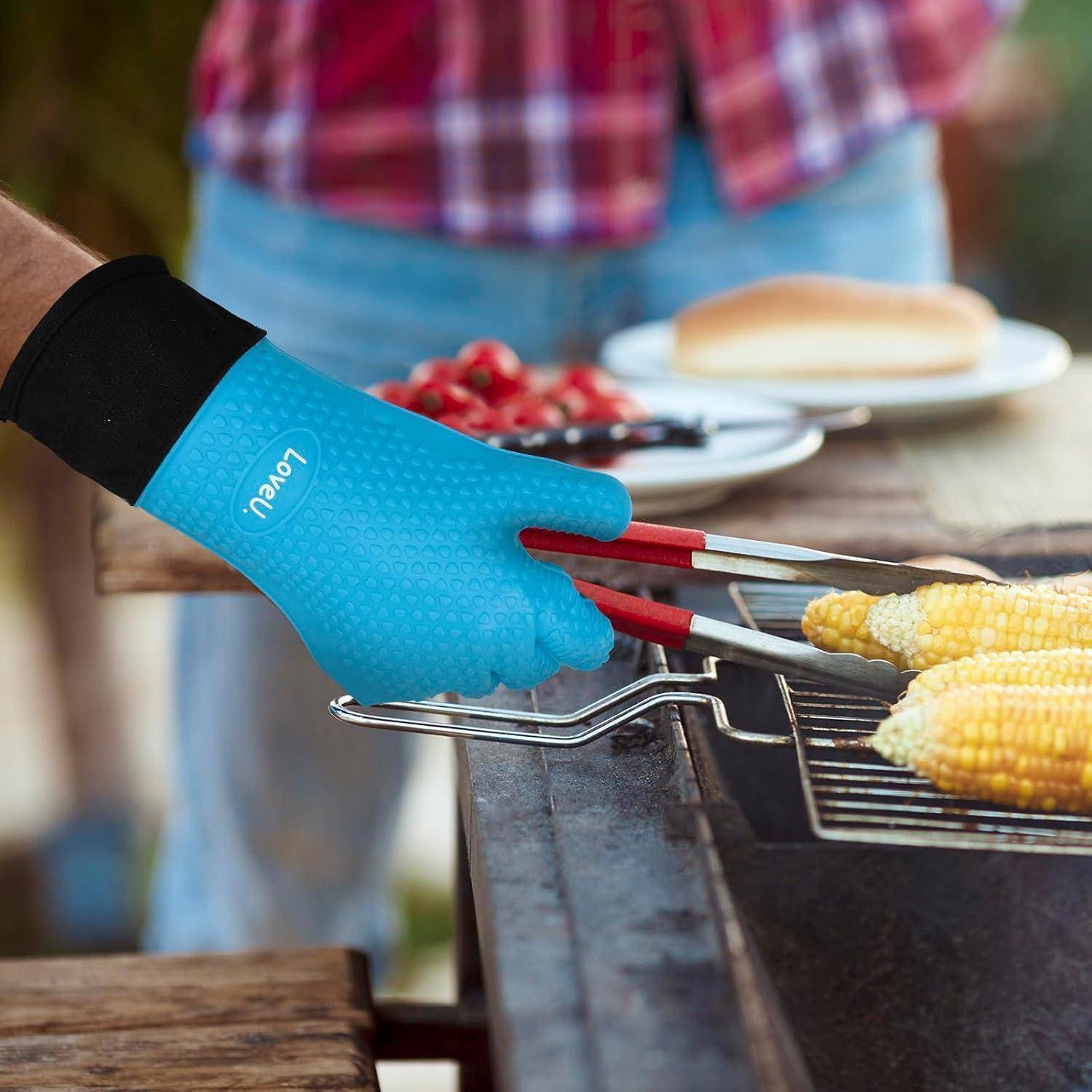 Blauer Grillhandschuh, der mit einer Zange Maiskolben auf einem Außengrill dreht.