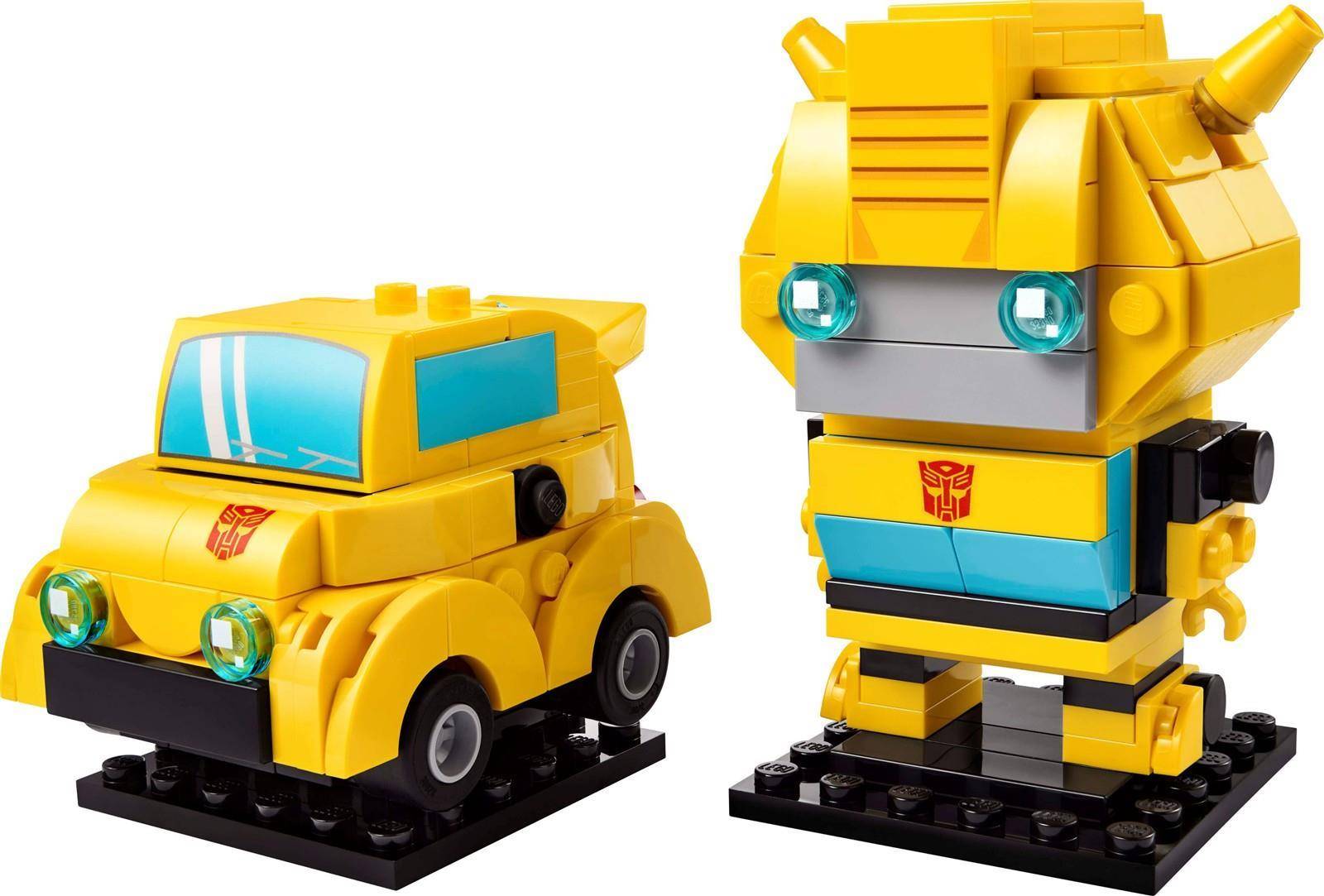 Zwei gelbe LEGO-ähnliche Transformer-Figuren auf schwarzen Basen: ein Auto auf der linken Seite und ein Roboter auf der rechten Seite, beide mit blauen Fenstern und Decepticon-Logos.
