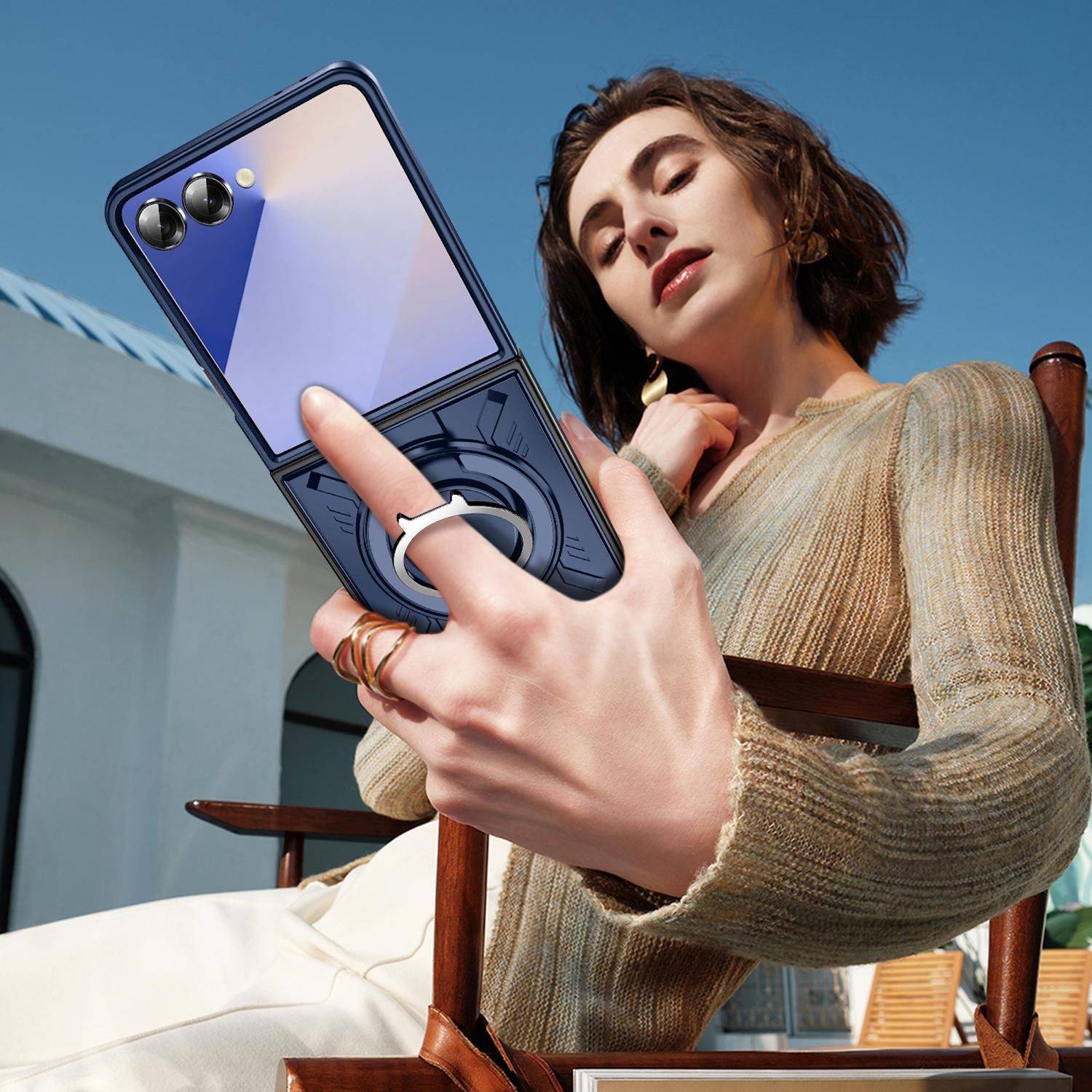 Frau, die ein Selfie mit einem faltbaren Smartphone macht, wobei die rückwärtigen Kameras des Telefons und der eingebaute Ringständer vor einem Himmel im Freien sichtbar sind.