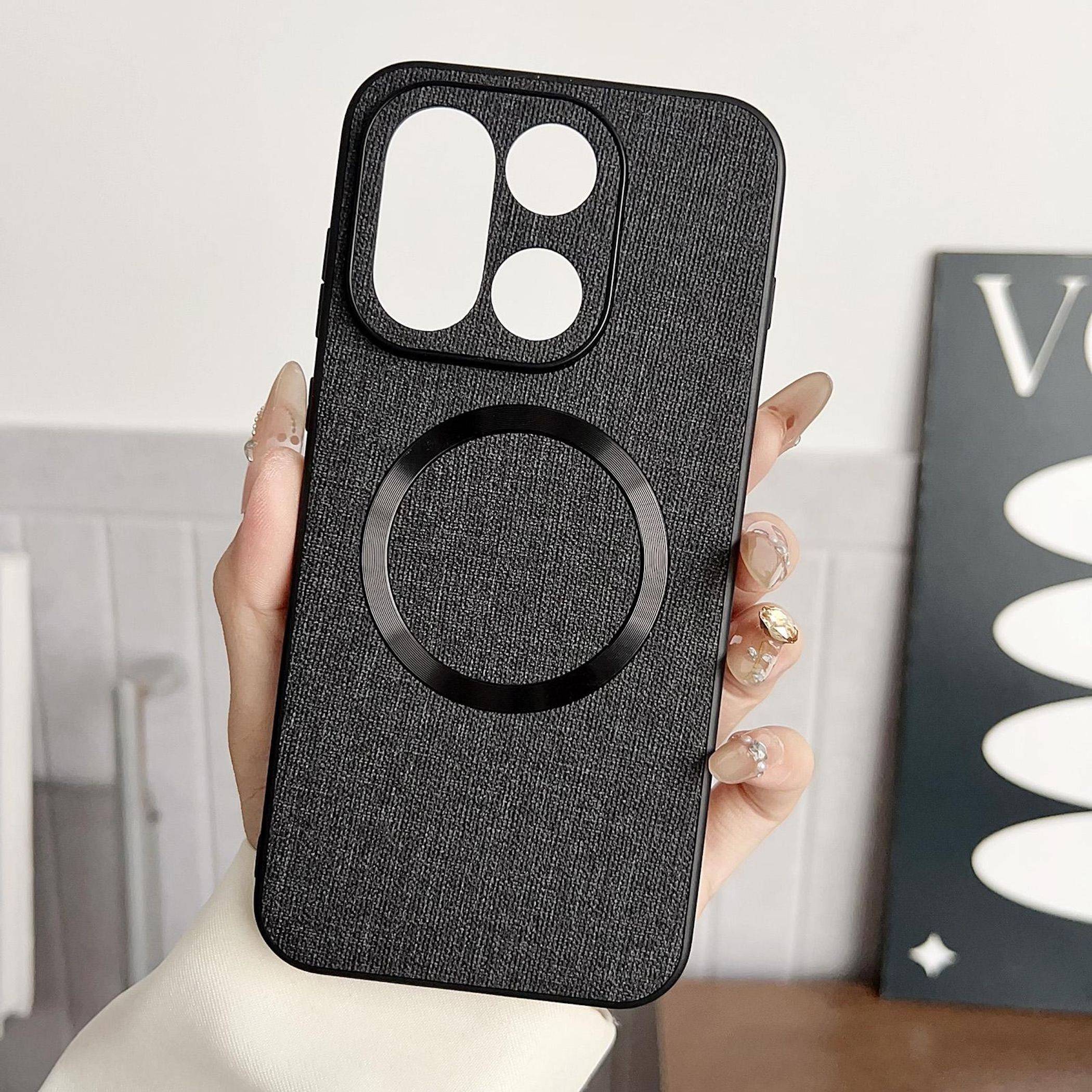 Hand, die eine schwarze strukturierte Smartphone-Schutzhülle mit einem großen kreisförmigen MagSafe-Ring und doppelten Kameraausschnitten hält.
