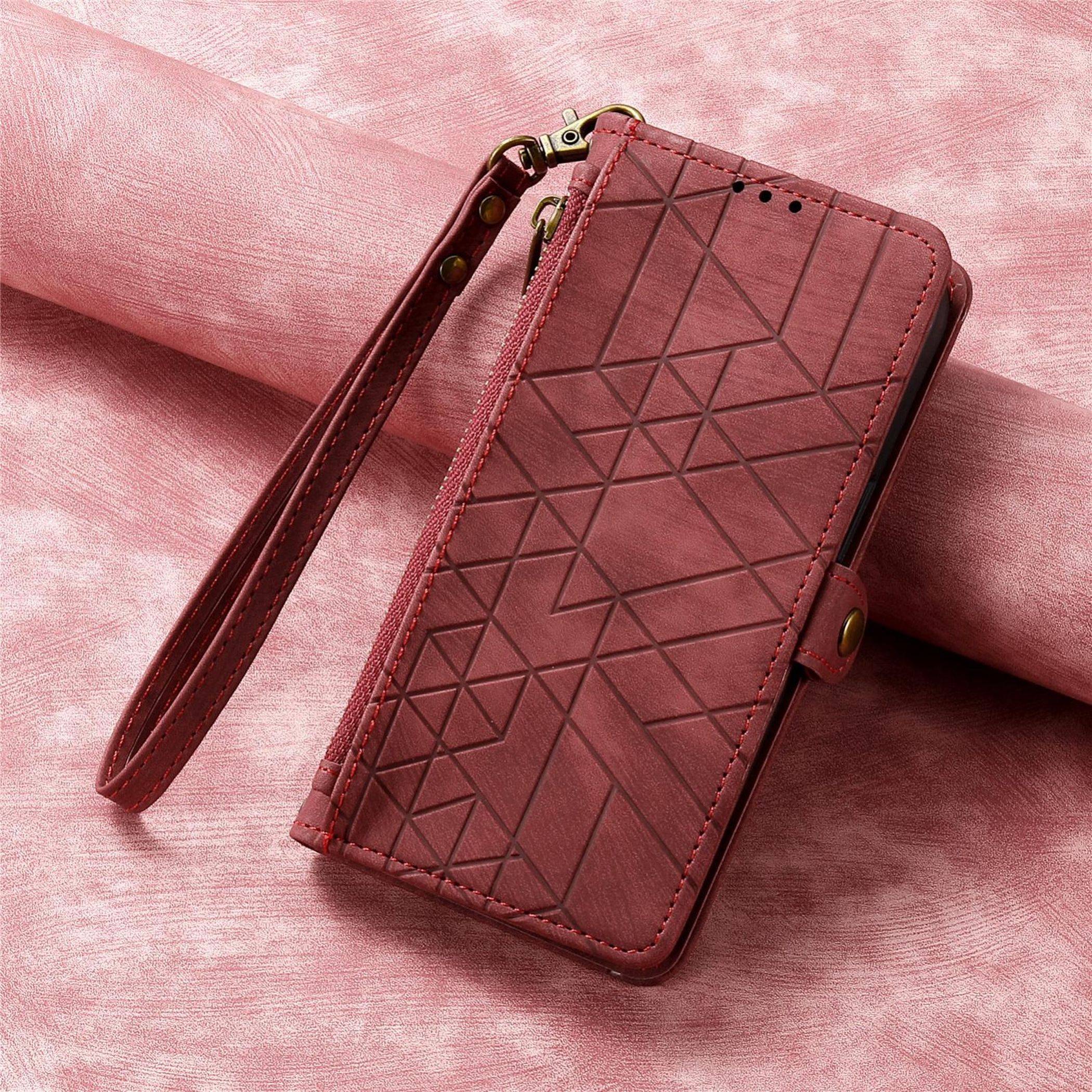 Burgunderrote Handy-Geldbörse mit geometrischem Muster und Handgelenkschlaufe auf rosa strukturiertem Hintergrund.
