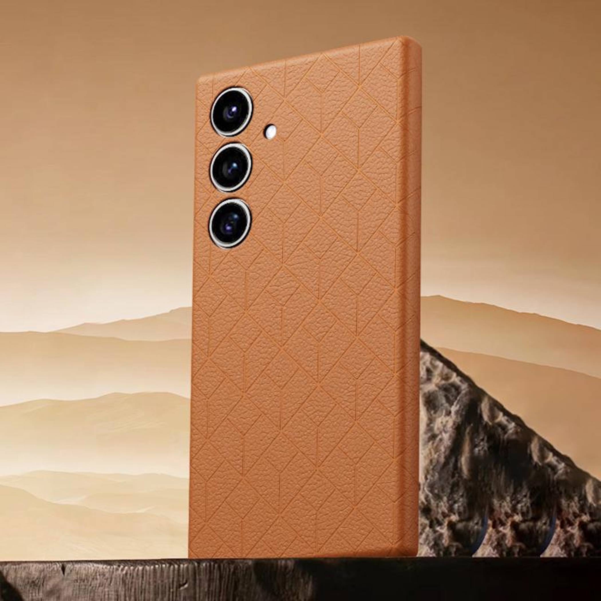 Ein beiges strukturiertes Smartphone-Etui mit drei hinteren Kameraobjektiven steht vor einer wüstenartigen Landschaft und Felskulisse.