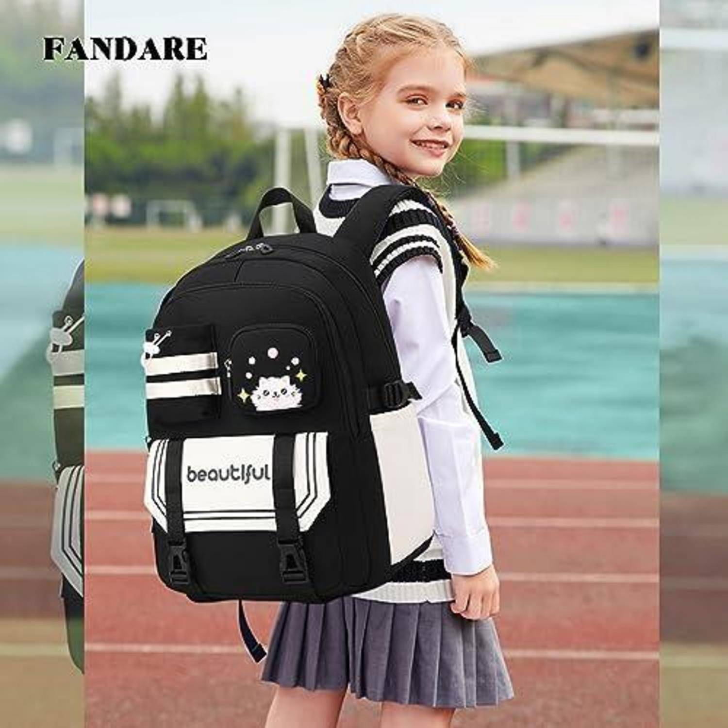 Junges Mädchen, das auf einer Strecke steht, mit einem schwarzen Schulrucksack, von der Seite gezeigt und lächelnd; der Rucksack hat das Wort 