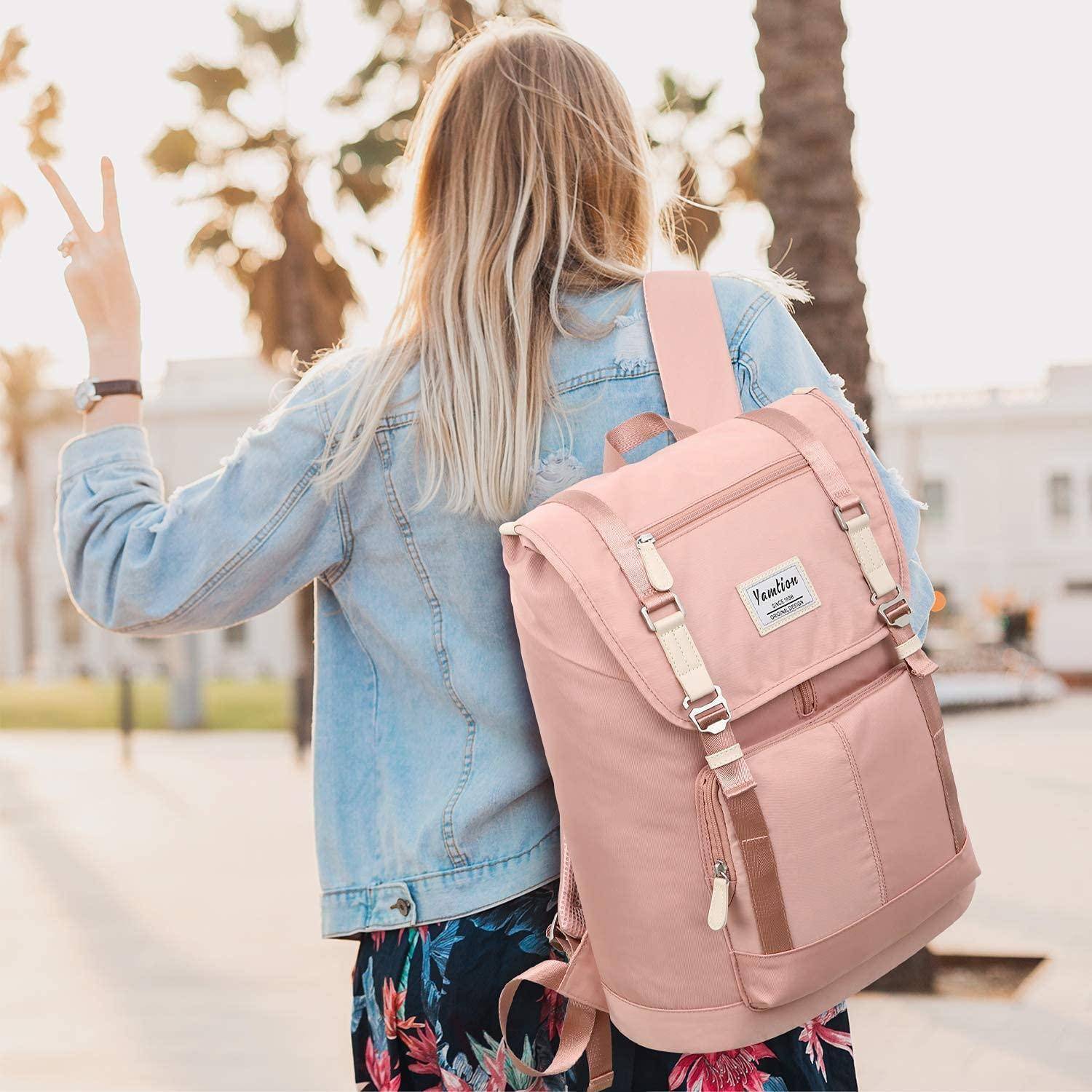 Rückansicht einer blonden Frau, die einen rosa Rucksack und eine Jeansjacke trägt, die draußen im hellen Sonnenlicht ein Friedenszeichen macht.
