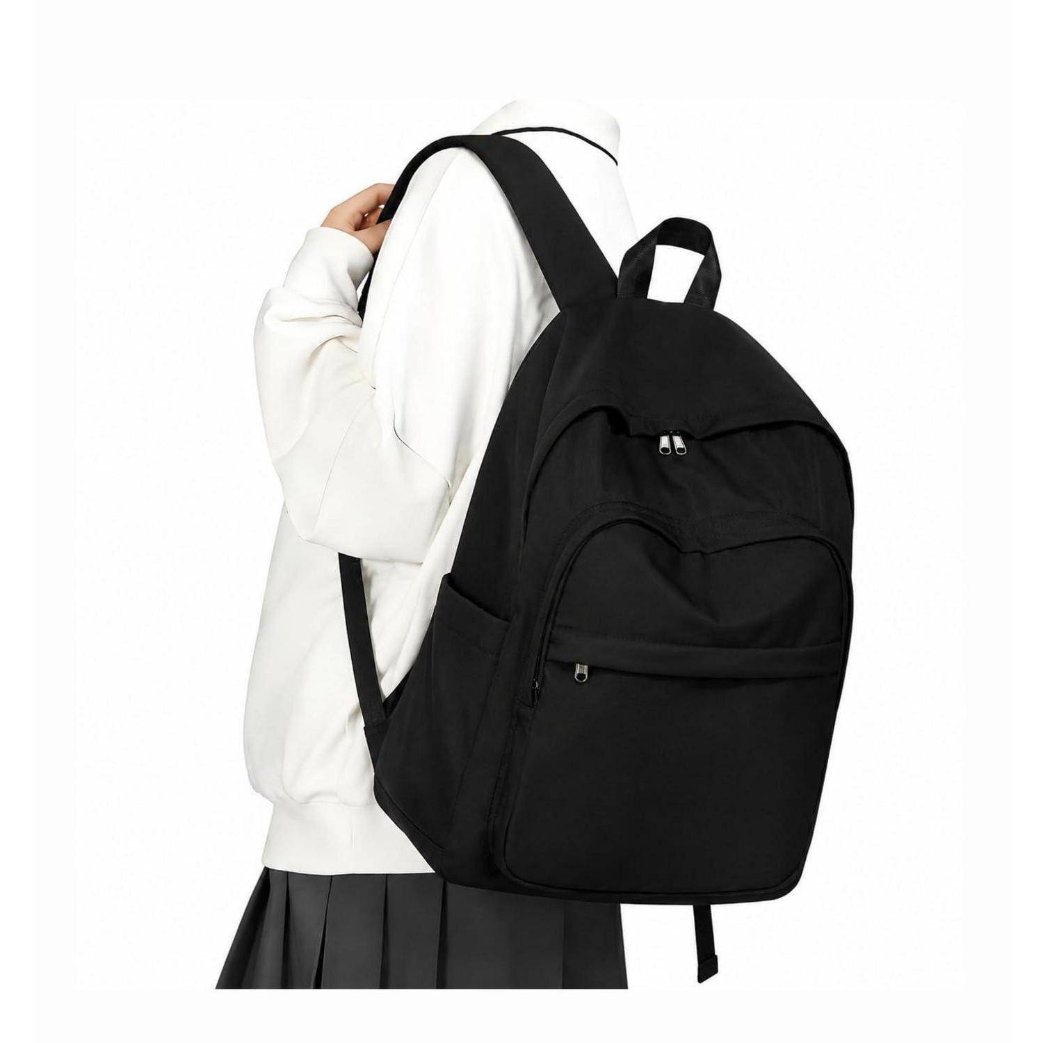 Person trägt einen schwarzen Rucksack über einem weißen Hoodie und einem dunklen Rock, vor einem weißen Hintergrund gezeigt.