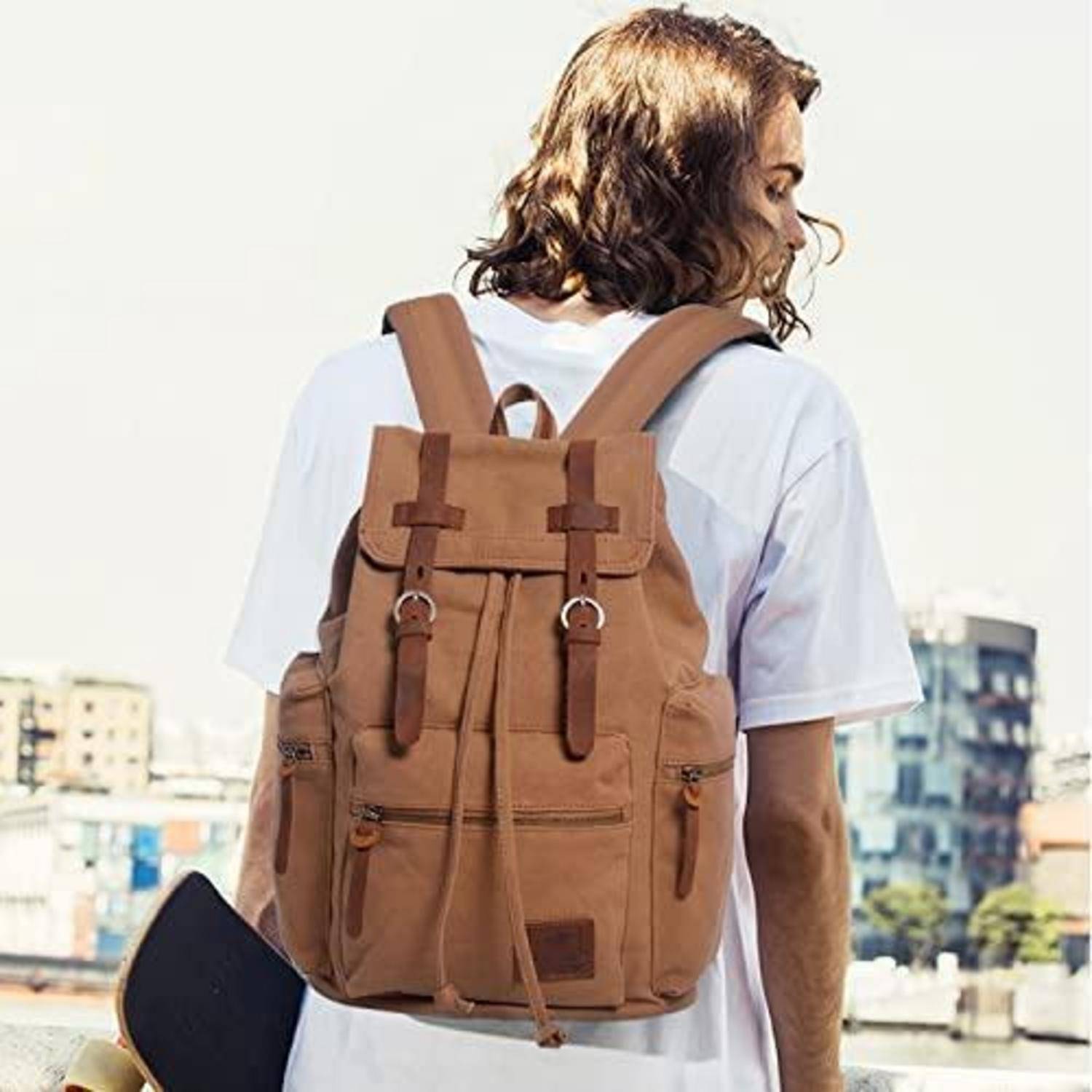 Person, die von hinten zu sehen ist, trägt einen braunen Rucksack über einem weißen T-Shirt, fotografiert im Freien in einer städtischen Umgebung.